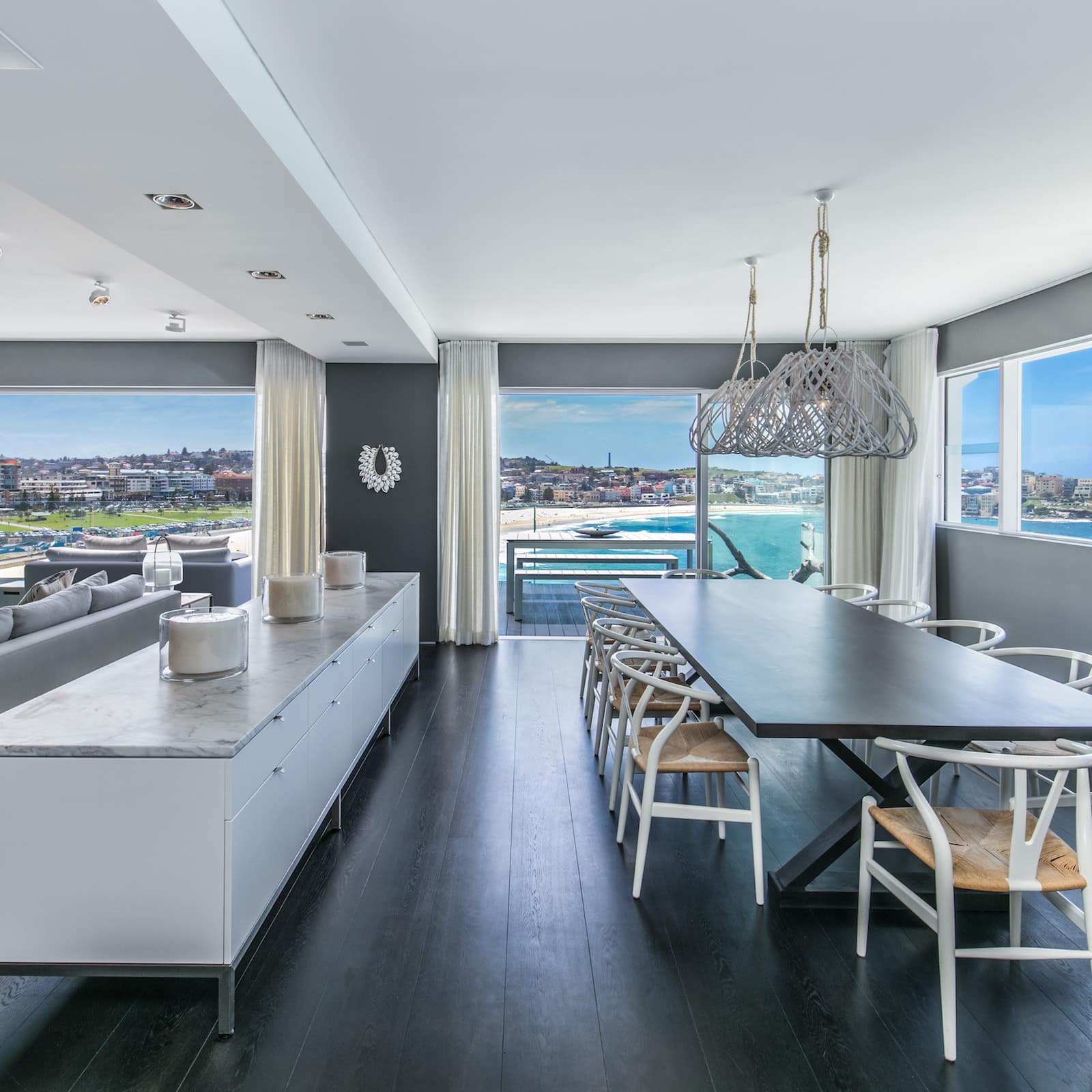 Penthouse open living and dining area with sofa, hardwood floors and views of Bondi Beach