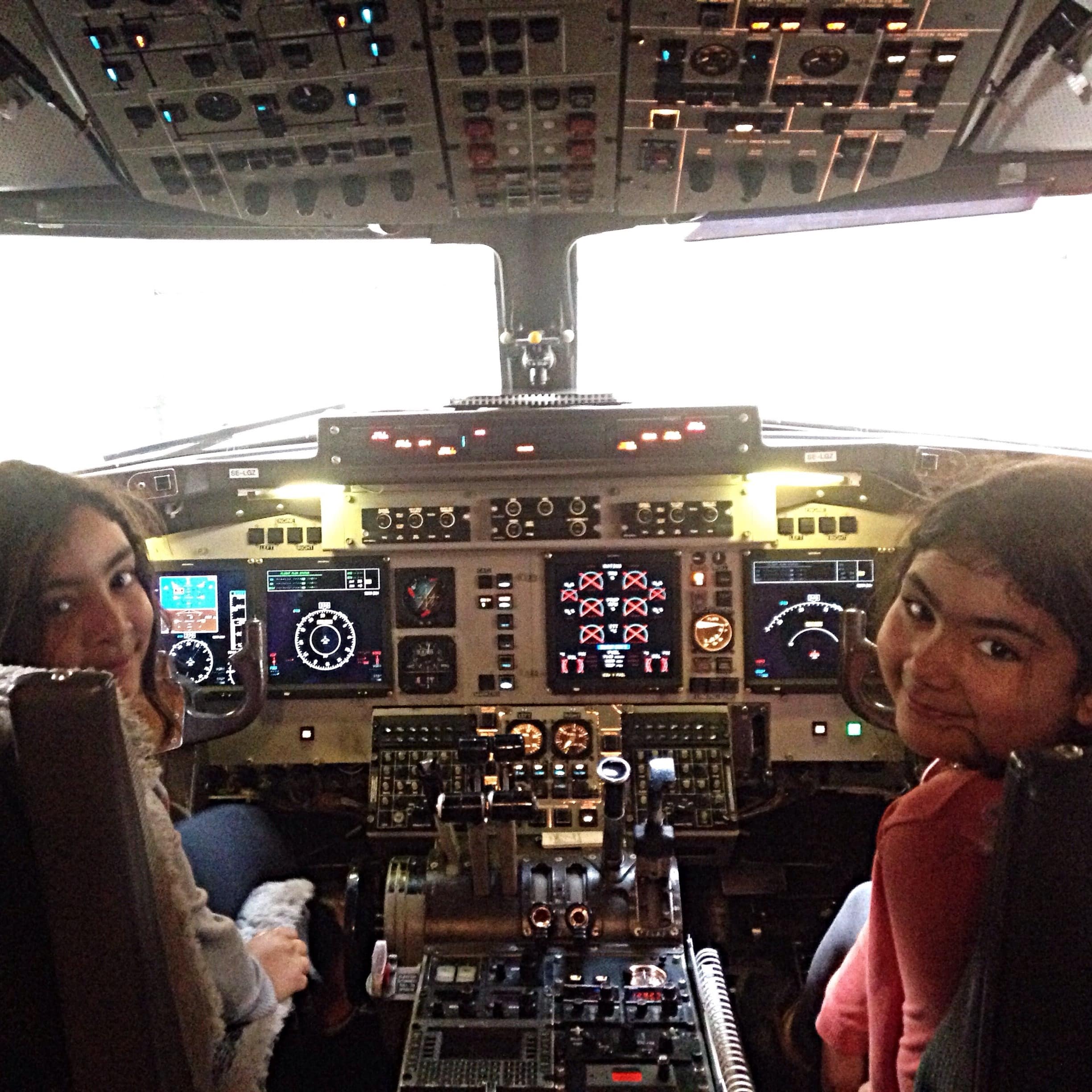 Two young girls sitting in the cockpit of plane