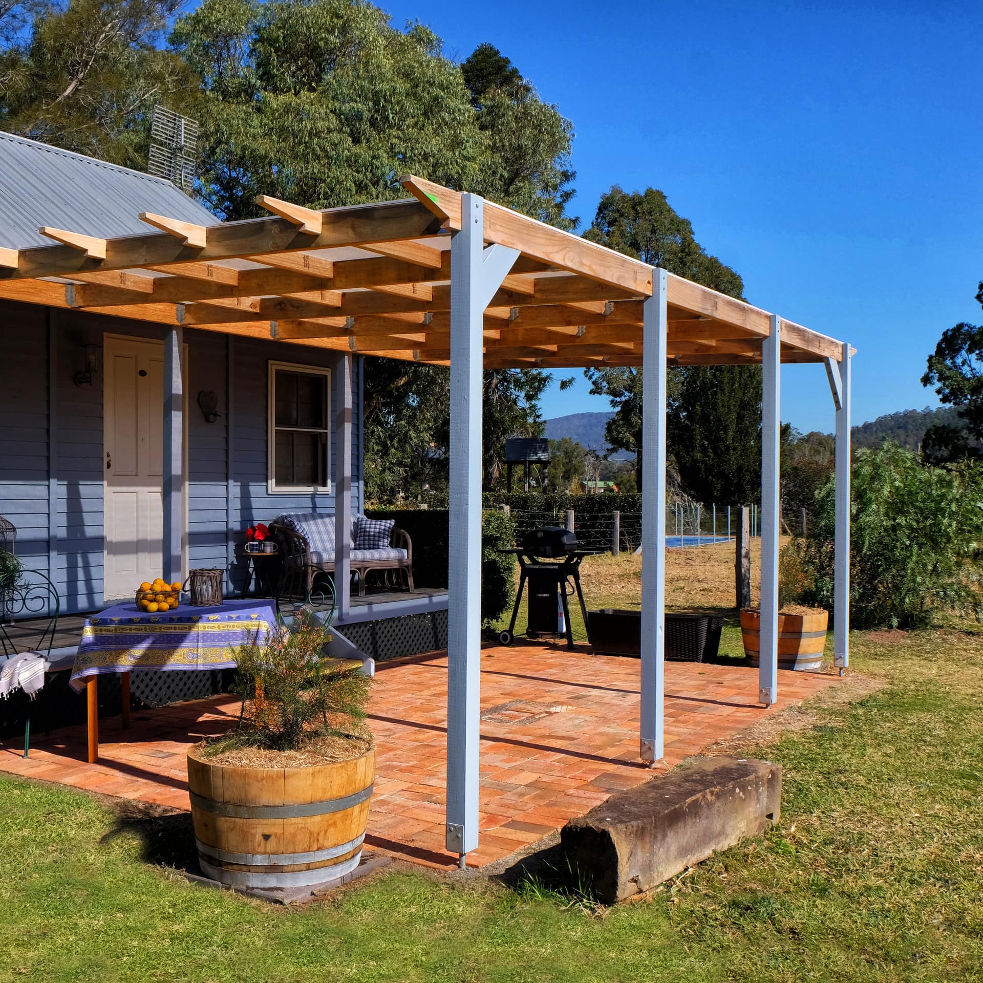 One-storey cabin with veranda overlooking rolling hills and tall trees