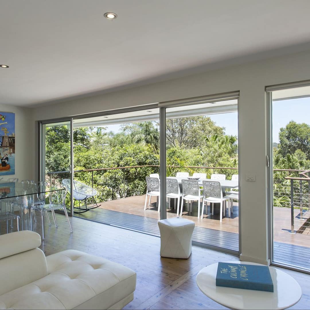 Interior of Palm Beach house with hardwood floors, white leather sofa, open dining and ocean views