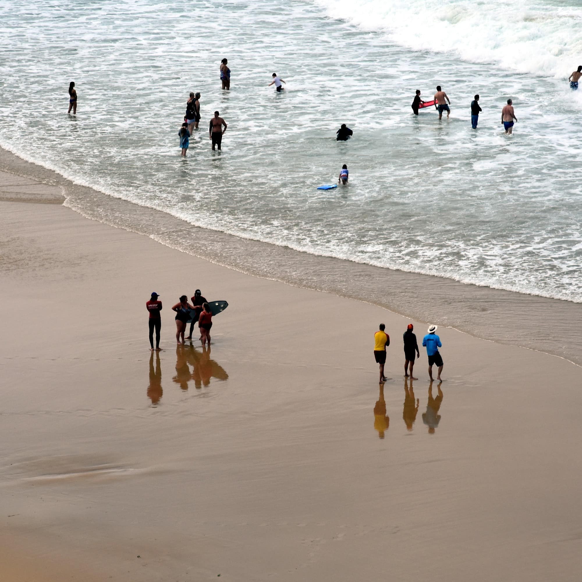 People relaxing swimming and sun bathing on Newcastle Nobbys beach.
