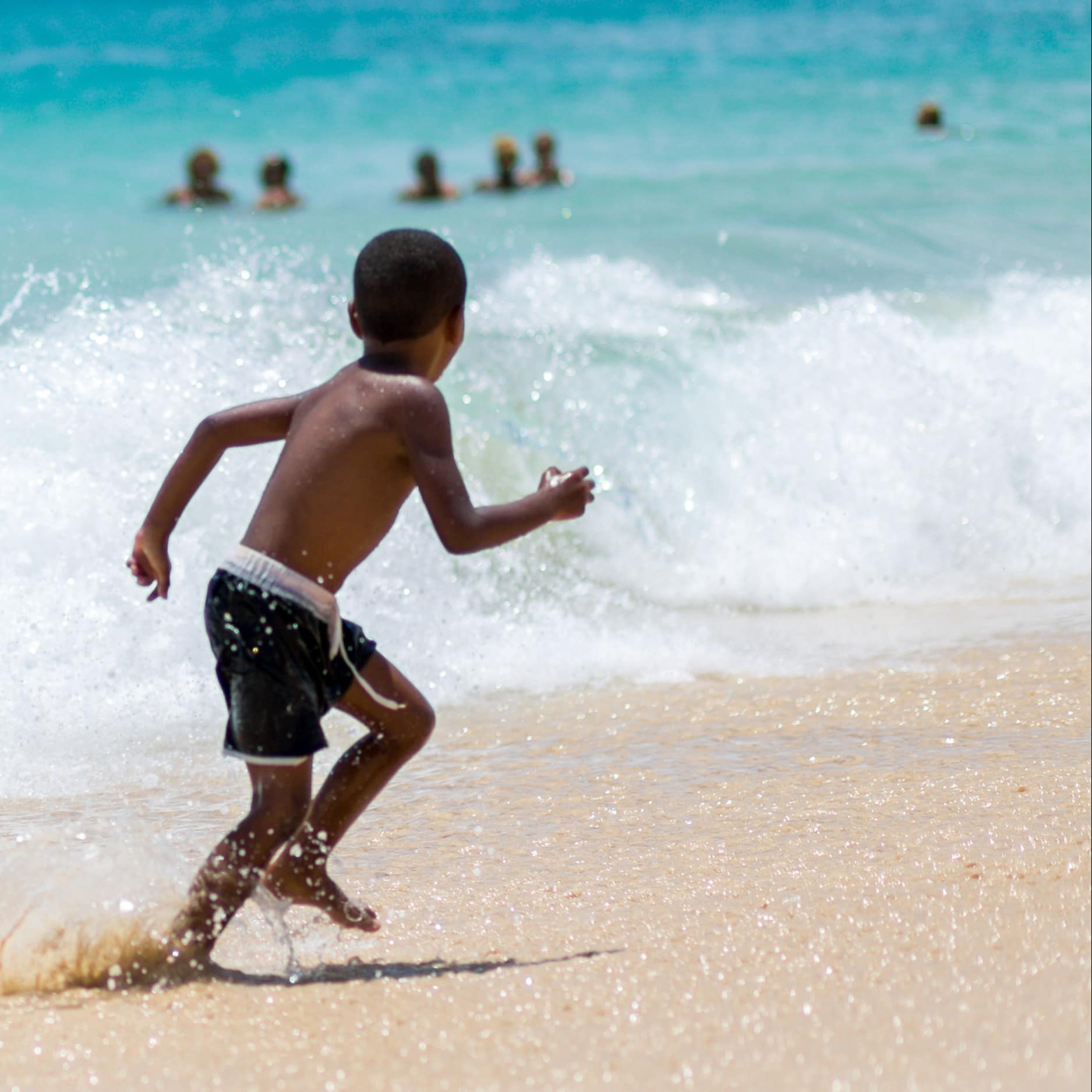 Little boy running from waves
