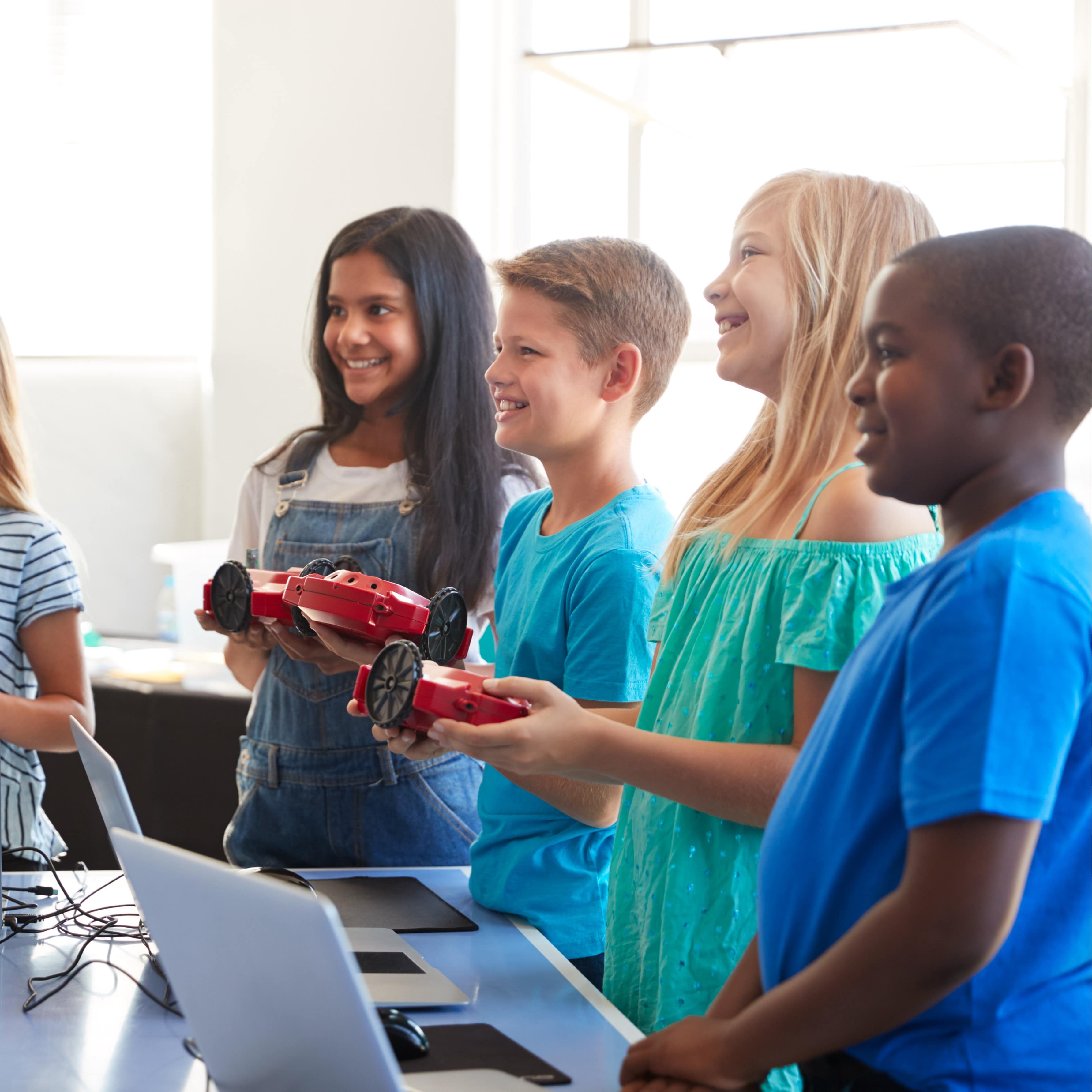 Group of multicultural students learning to program a robot vehicle