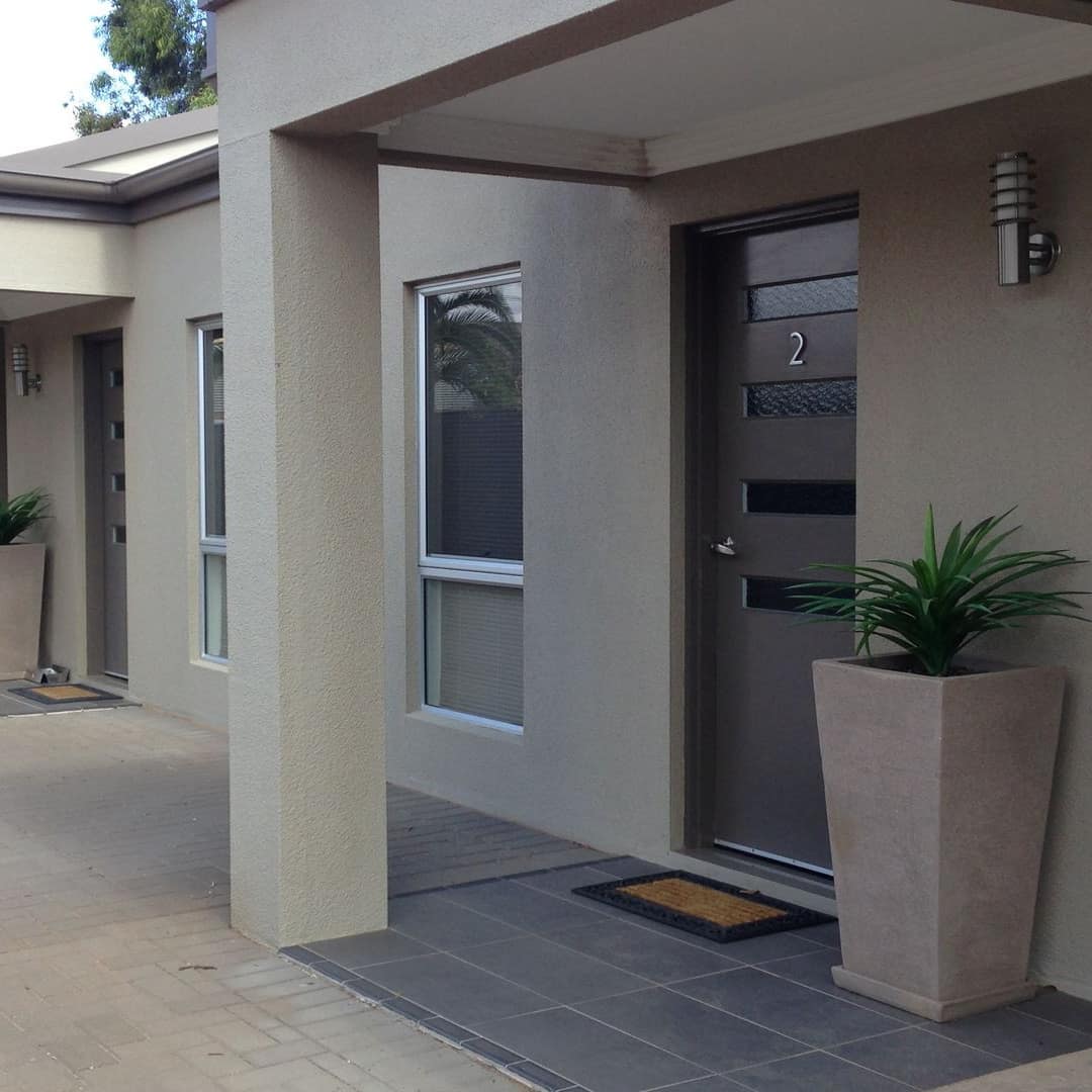 Exterior of 2-bedroom apartment with warm gray stucco, tiled entryway, and a planter by the door.