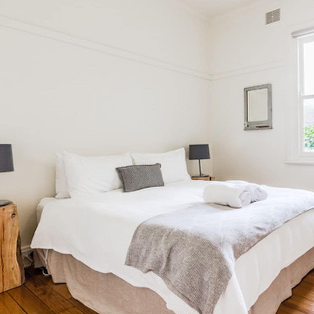 Rustic bedroom with hardwood floors, a king size bed, white and grey bedding, and a vintage green dresser.