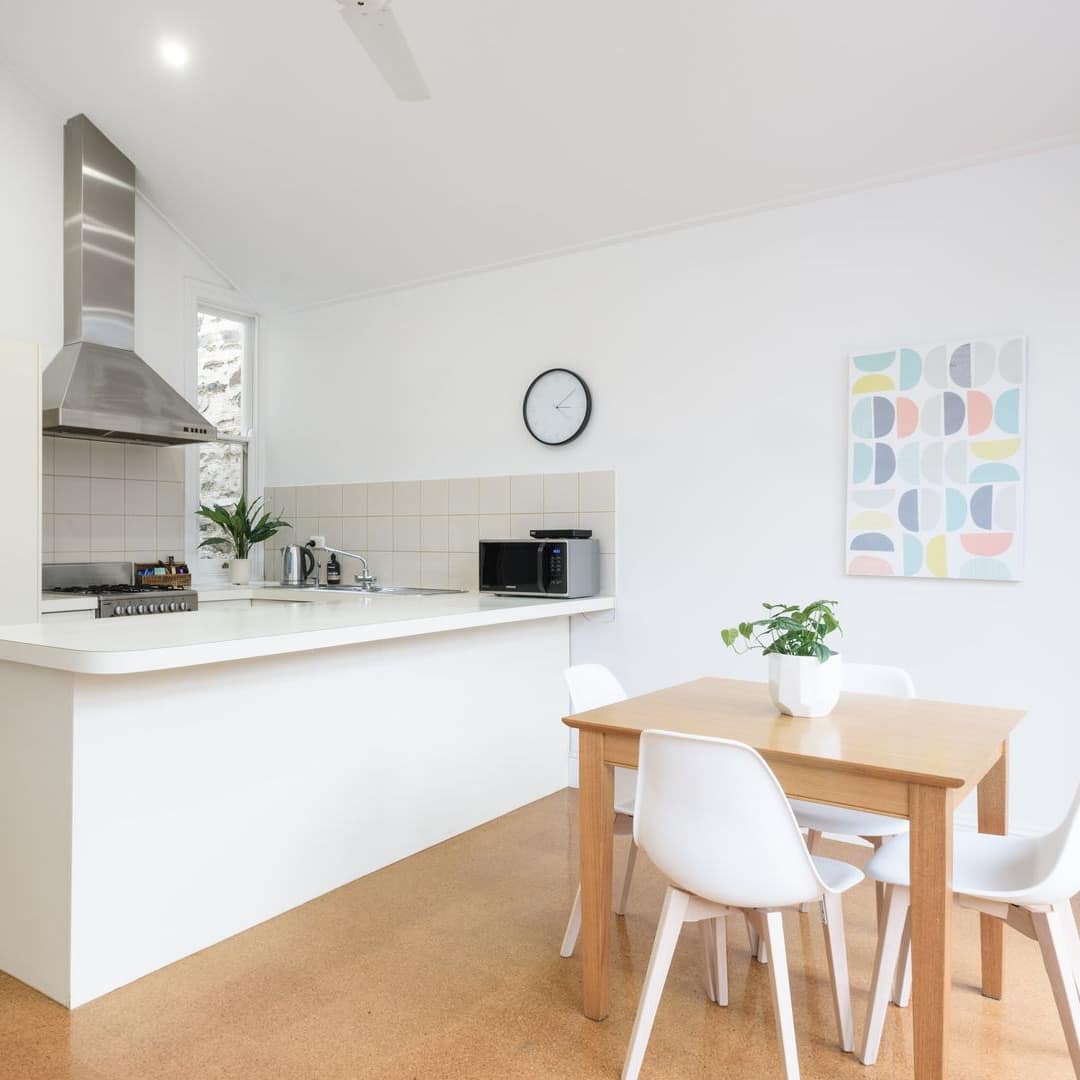 Modern kitchen and dining room with hardwood floors, wooden dining set, and white kitchen cabinets.