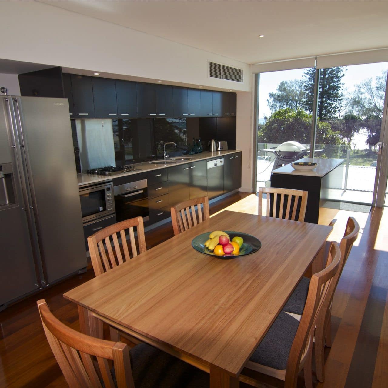 Kitchen and dining room with hardwood floors, wood dining room set, black cabinets, and stainless steel appliances.