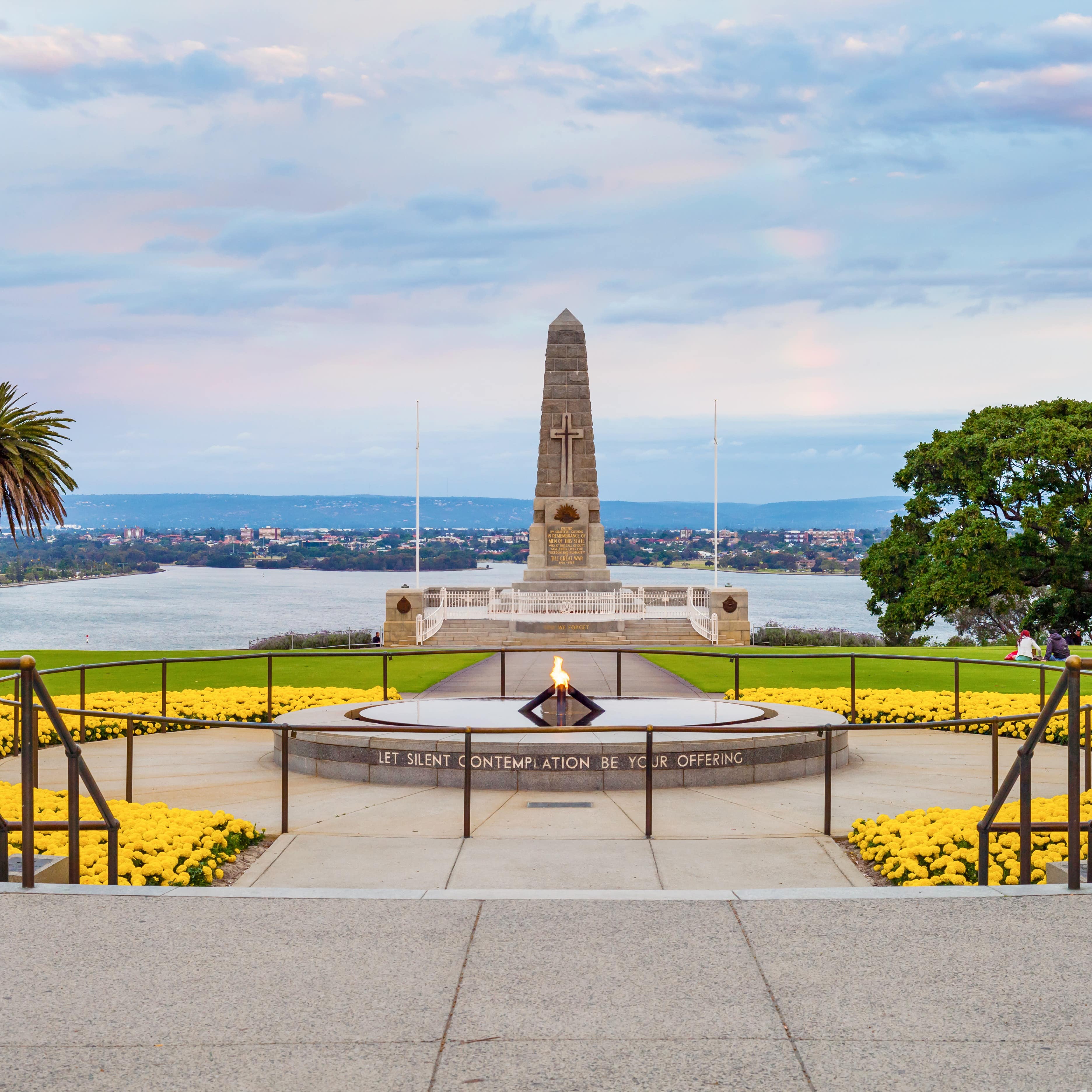 The eternal flame war memorial monument at Kings Park, Perth, Western Australia, with yellow flowers surrounding the flame walkway with sea in background