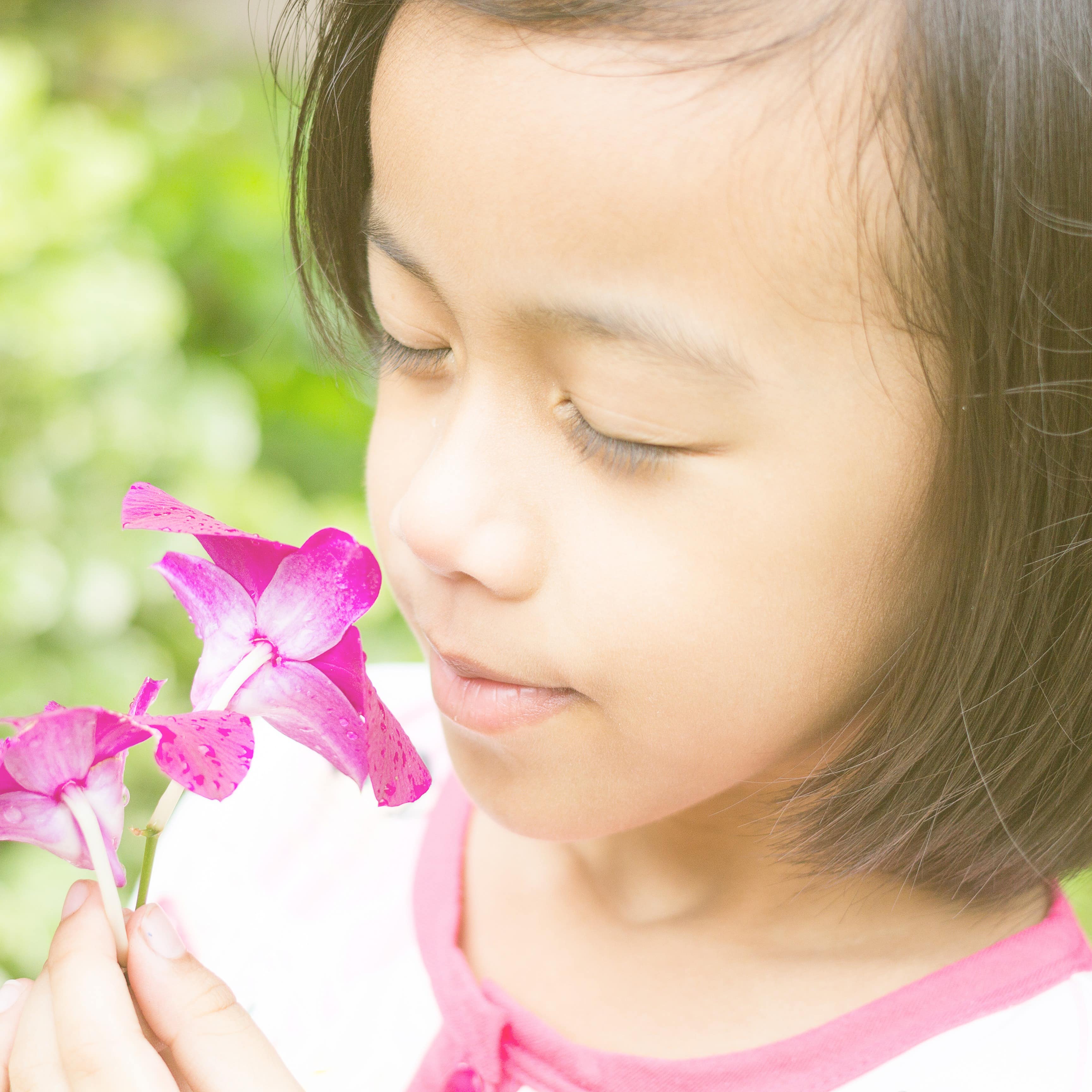 Young girl smelling a pink orchid
