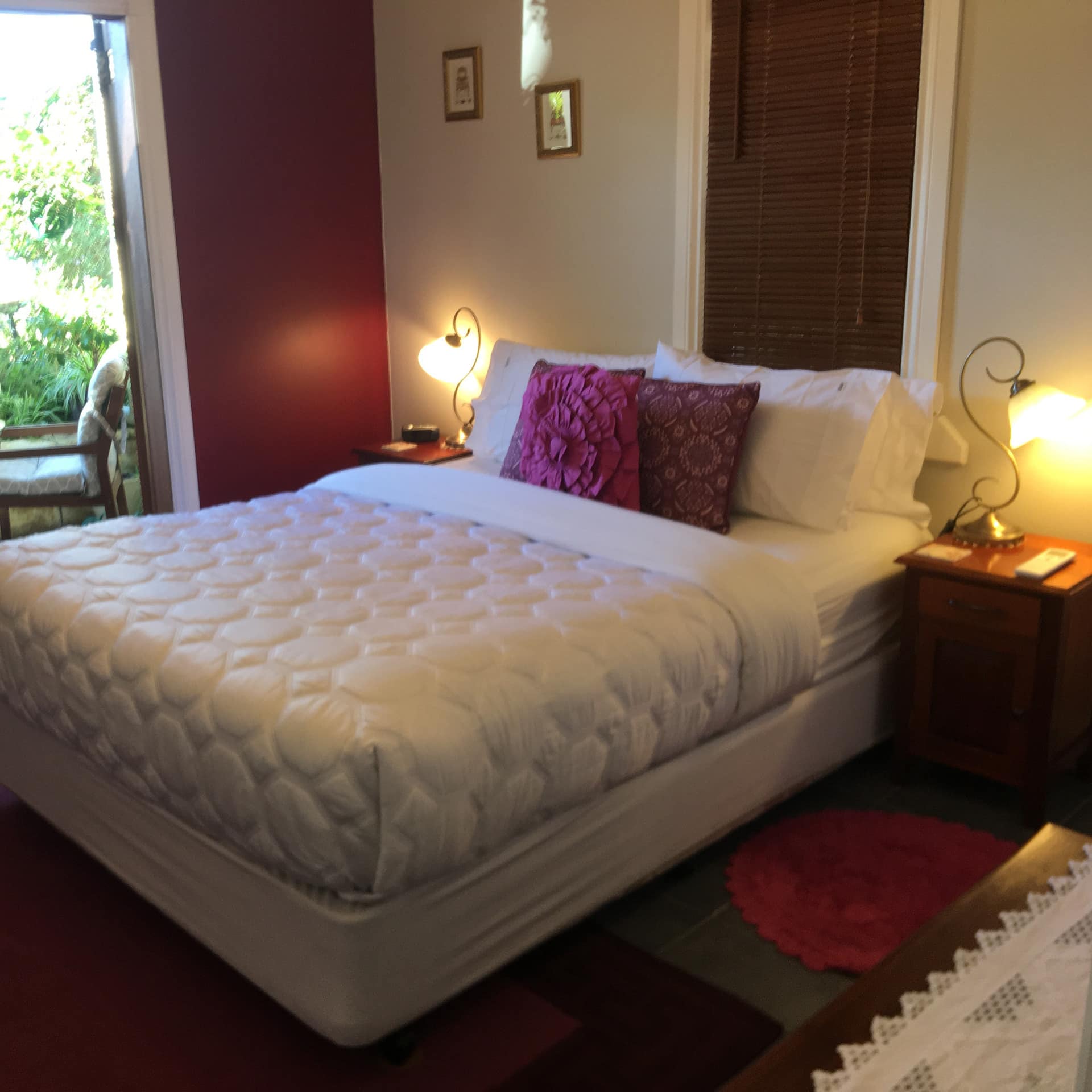 Bedroom with a red accent walls, red rugs, a king size bed, white and red bedding, and glass doors to a patio space.