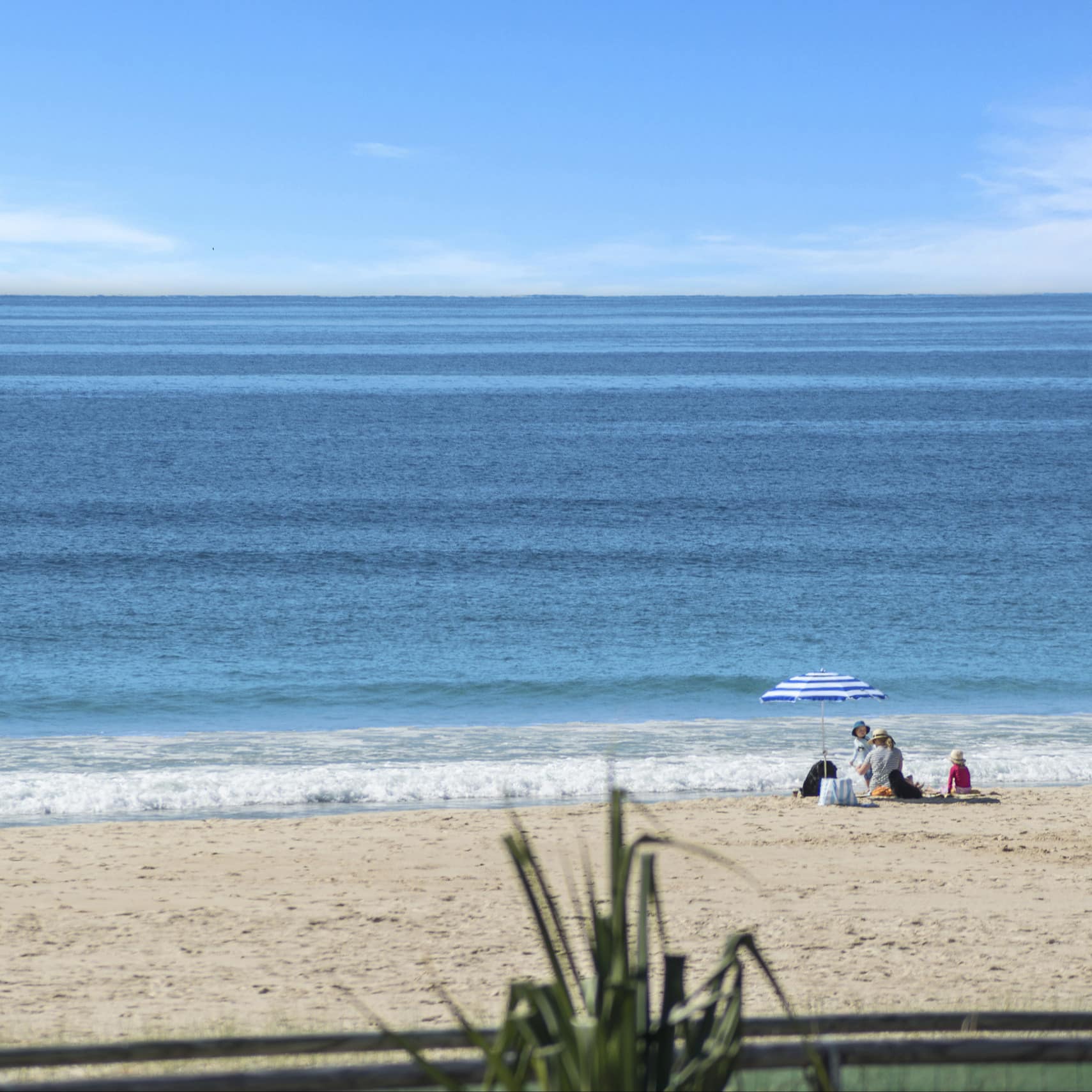 Beautiful view of calm sea and beachgoers under a beach umbrella at Main Beach on the Gold Coast