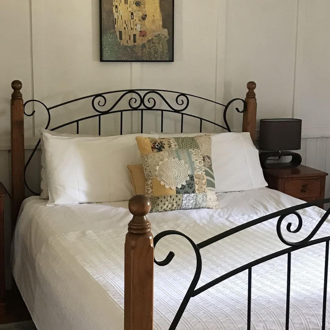 Rustic bedroom with a queen-size bed, white linen, quilted pillow, and matching wood bedside tables.
