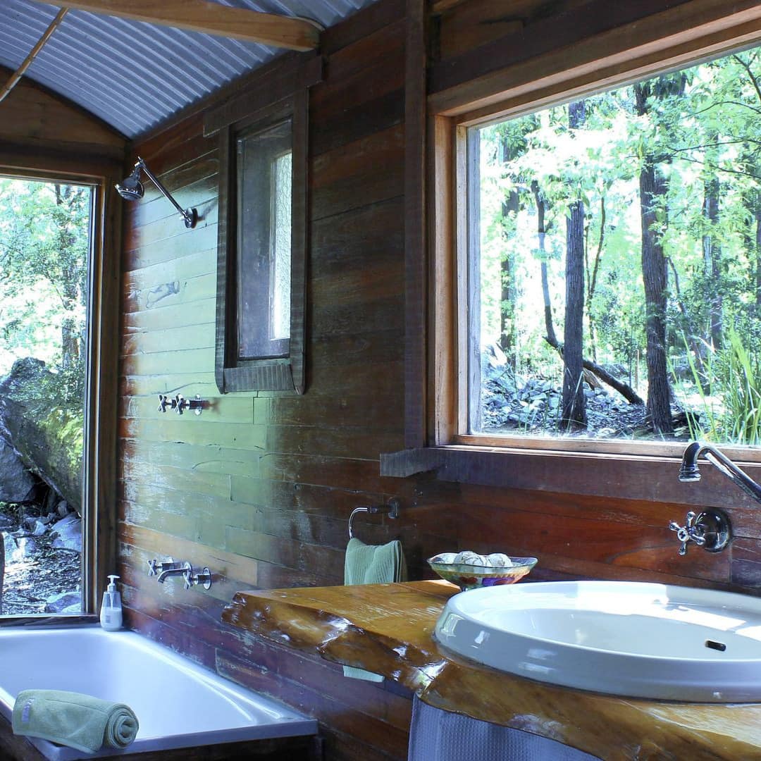 Deep bath perfect for two set into bay window with views of nature in bathroom