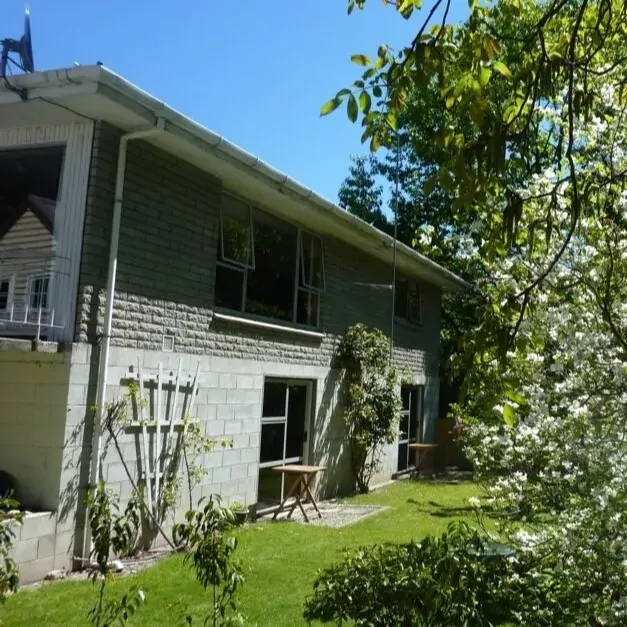 The back of a family lodge in Arrowtown with a white flower bush to the right
