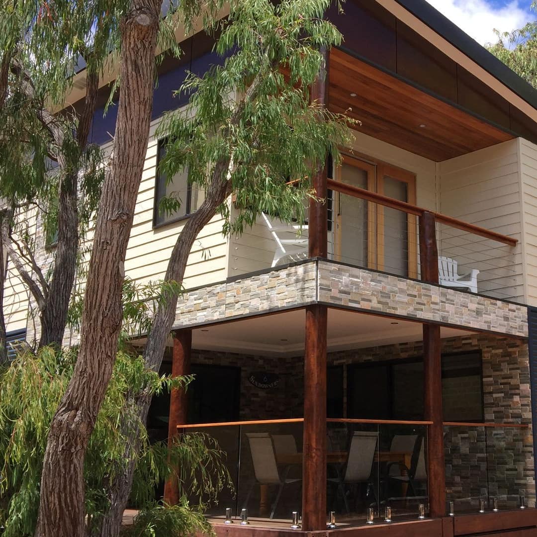 3-bedroom chalet surrounded by trees with covered porch overlooking garden