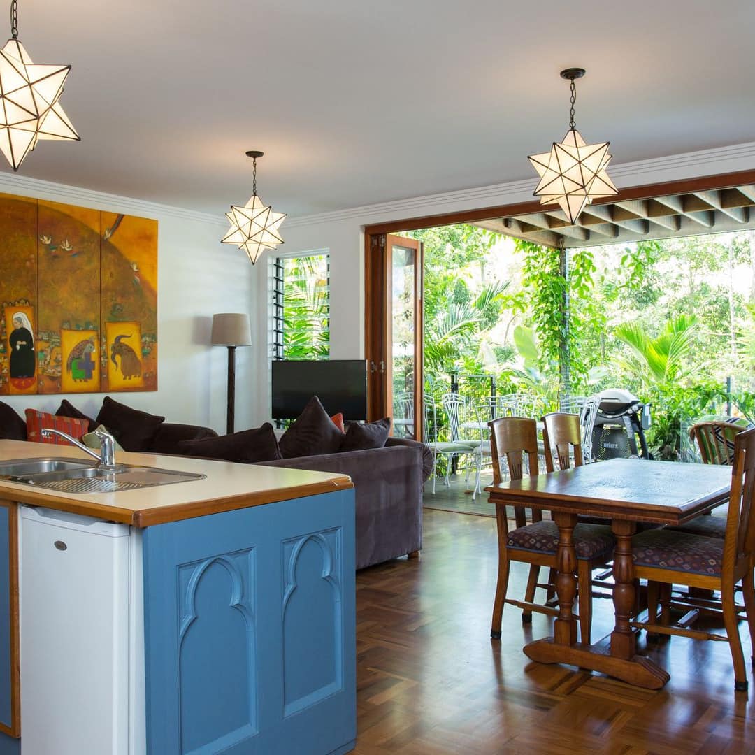 Colorful, open kitchen, living and dining room, parquet wood floors, open doors to lush yard, hanging moravian star lights.