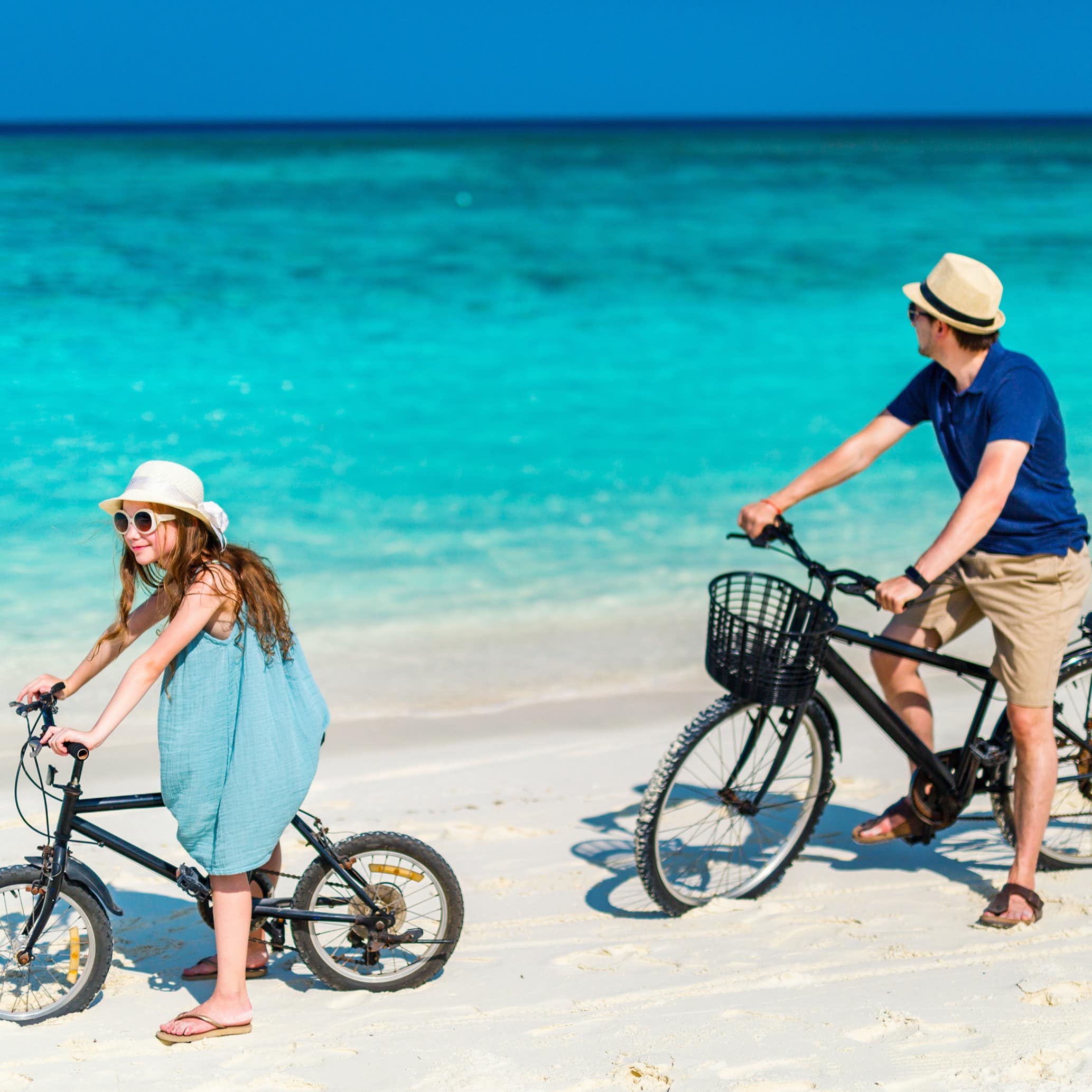 Father and daughter riding bikes at tropical beach