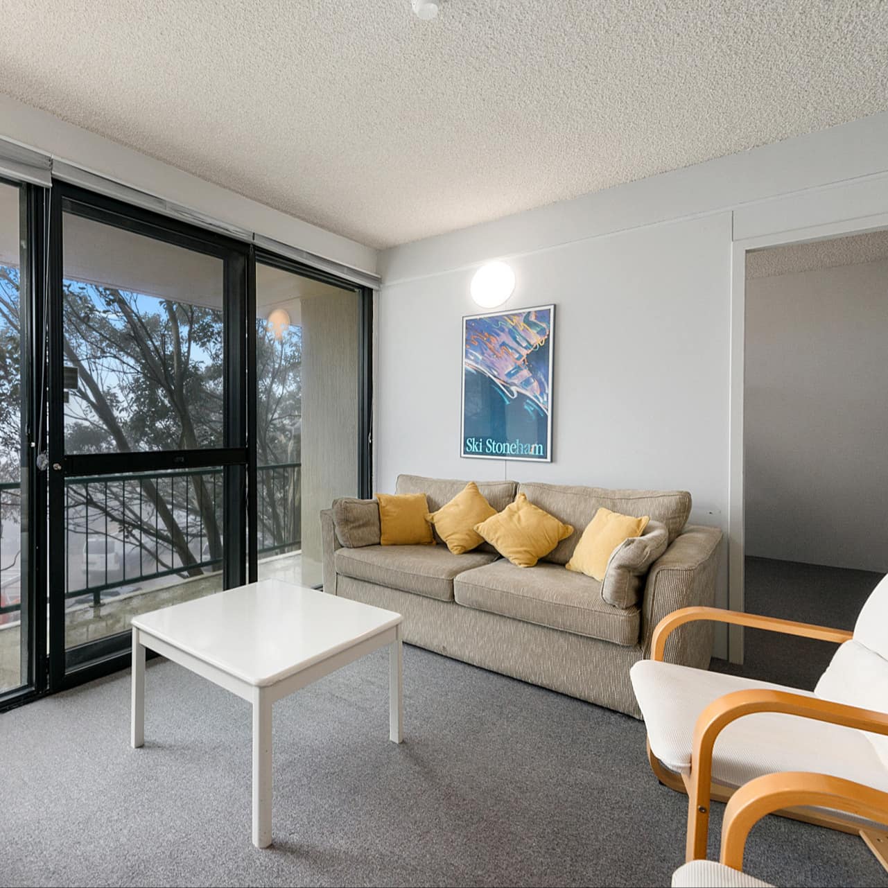 Hotel-style chalet apartment living room with a sofa, chairs and floor-to-ceiling windows looking out over the mountain