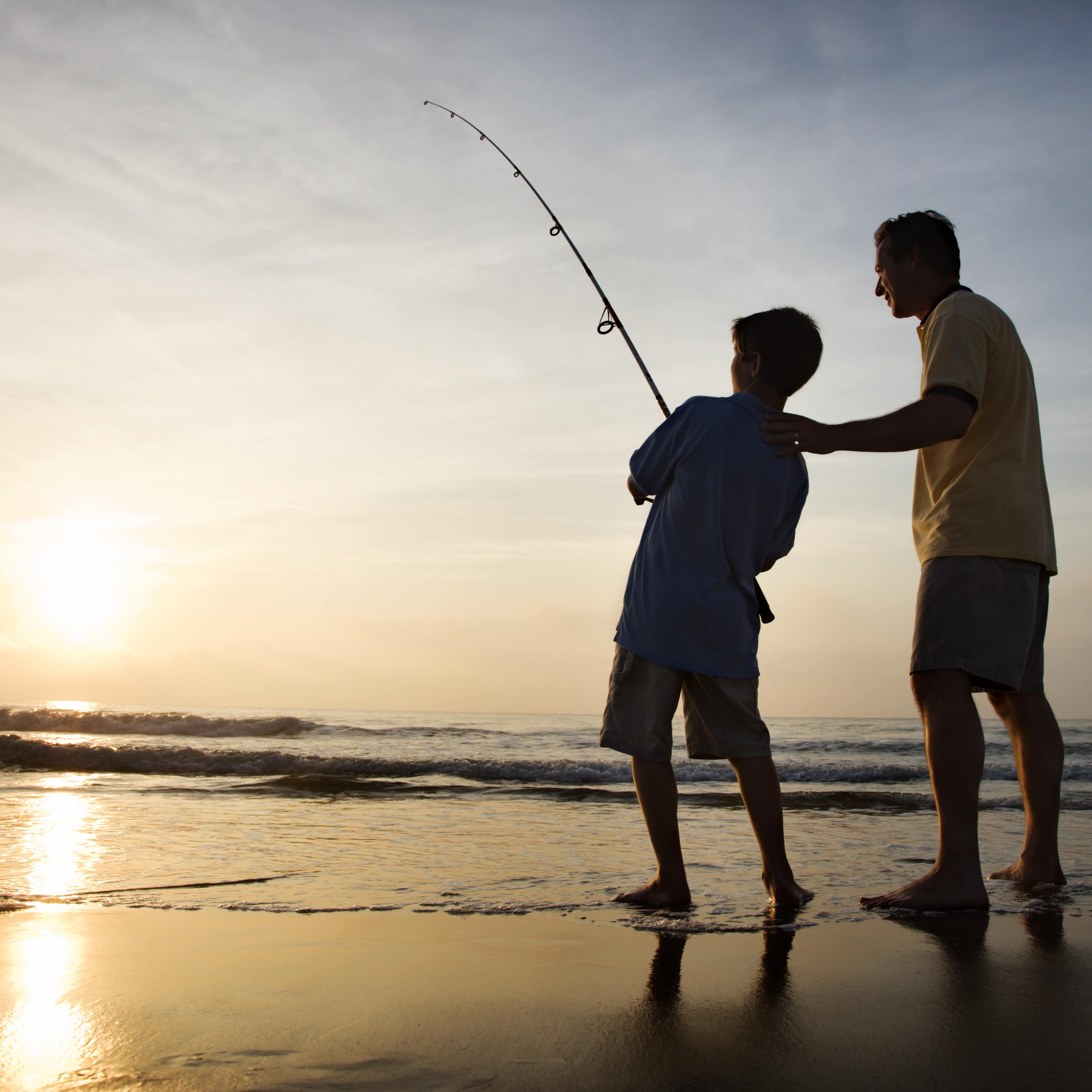 Man and boy surf fishing