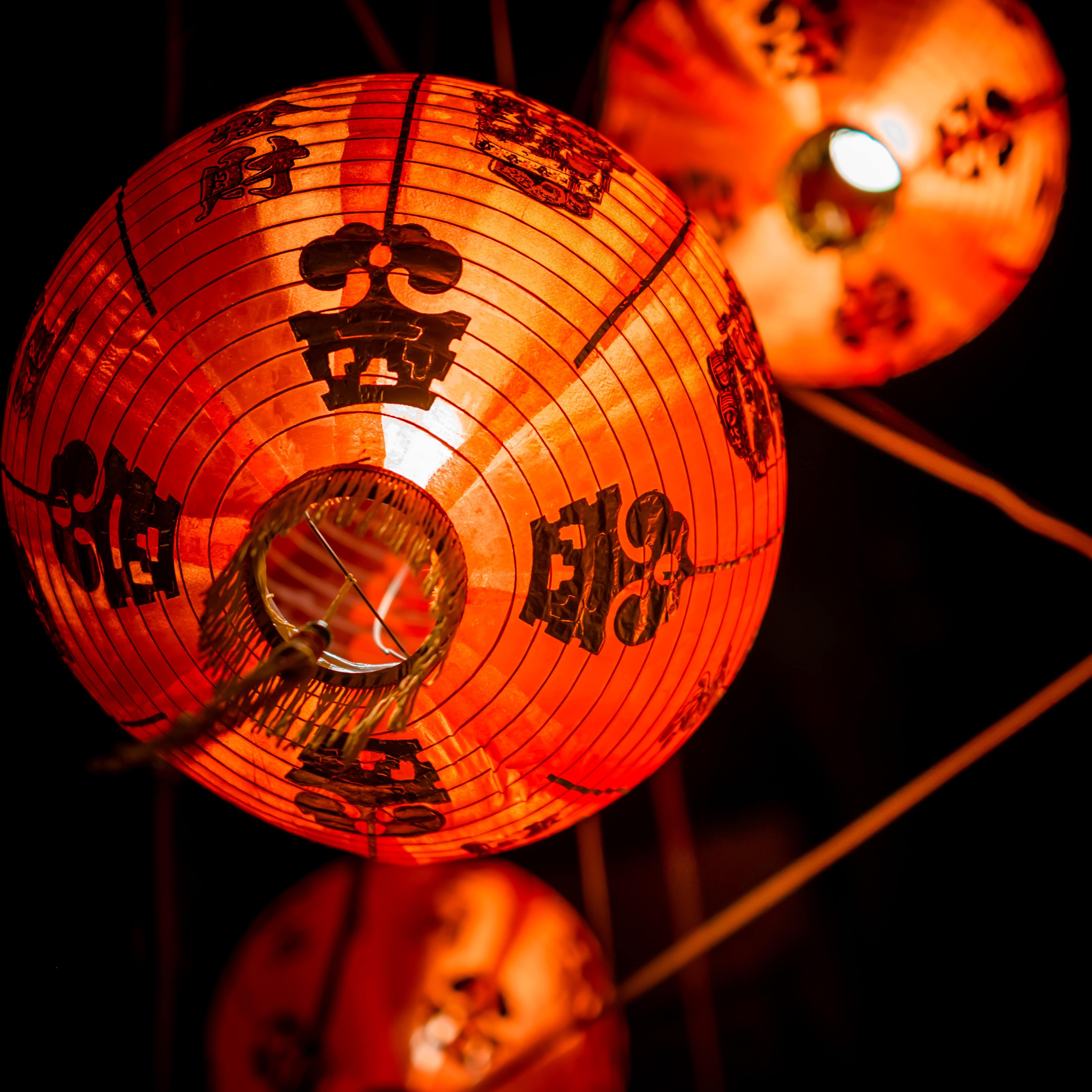 Close-up of red Chinese lamps that are lit looking up from floor at night
