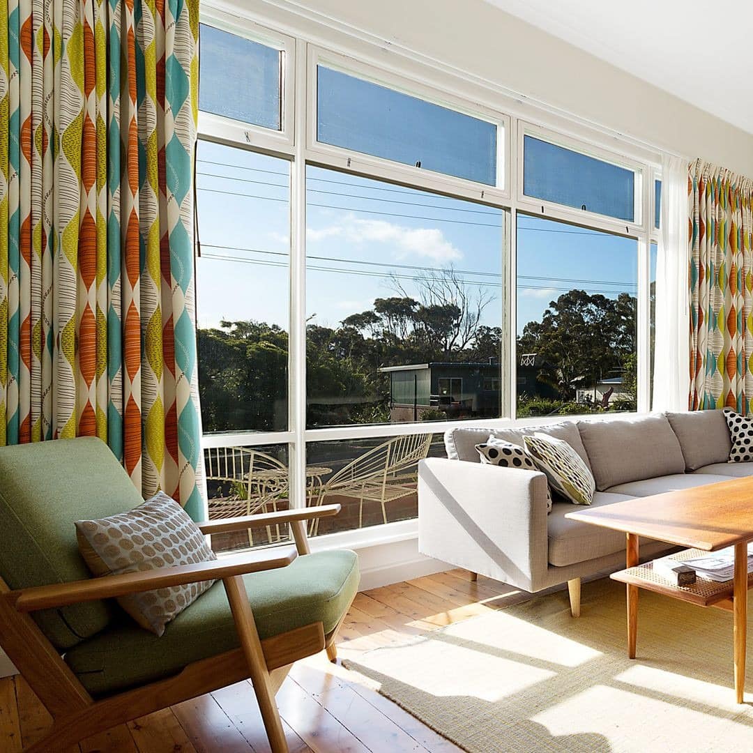 Retro-styled lounge well lit with sunlight pouring in from floor to ceiling window