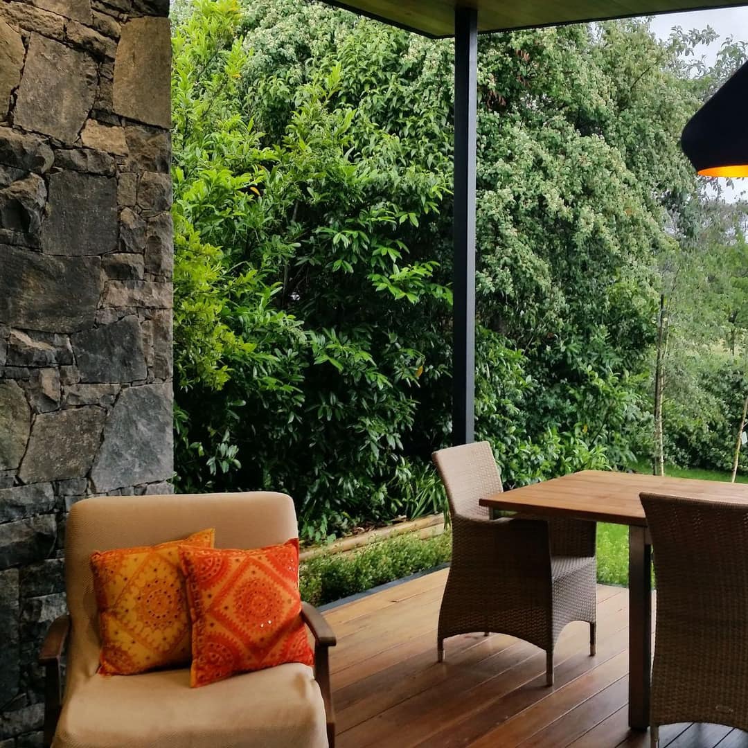 View of a wooden deck with a natural stone fireplace, wooden dining set and views of rural landscape.