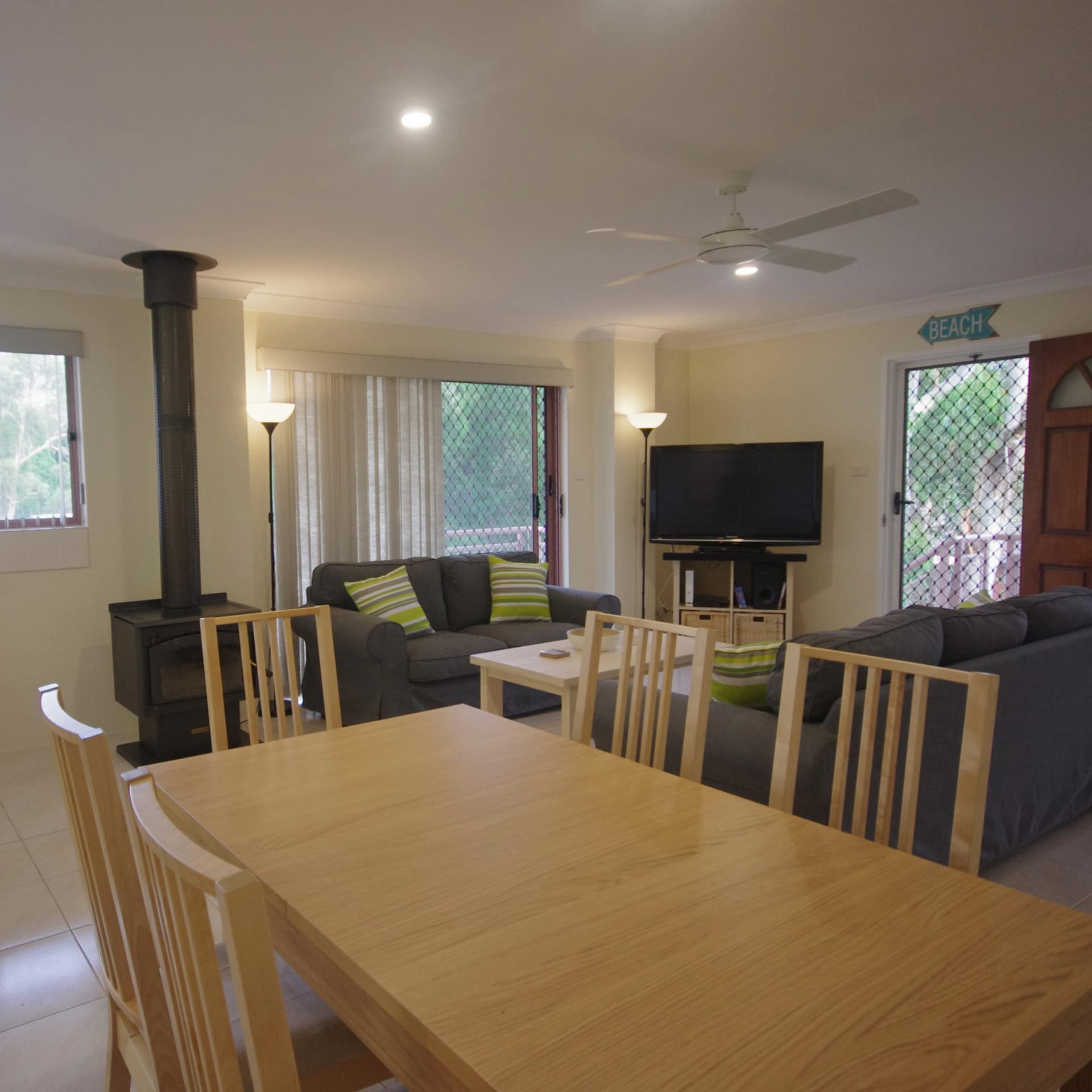 Large dining table in open kitchen to sitting room floor plan, light yellow walls and wood burning stove fireplace