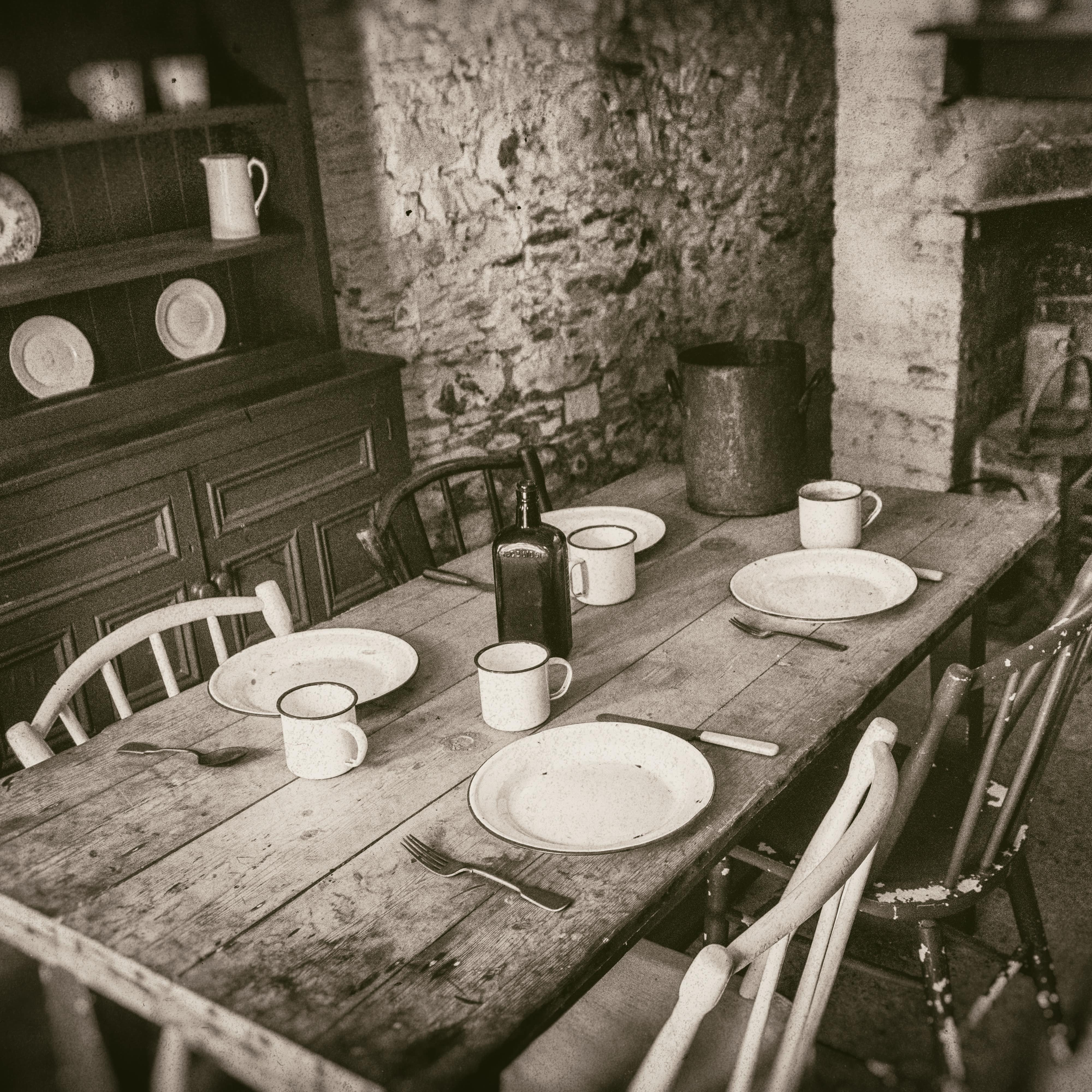 Sepia image of interior 19th century dining room with wooden table and fireplace