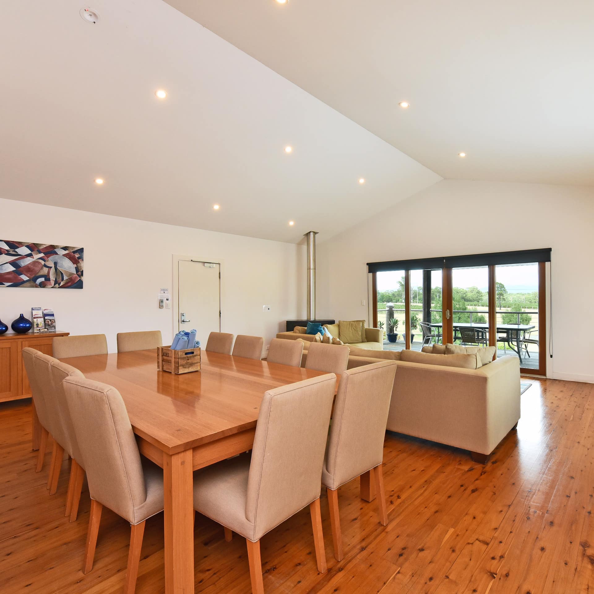 Spacious living area with large dining table, couches and a view of the outdoors through sliding-glass doors