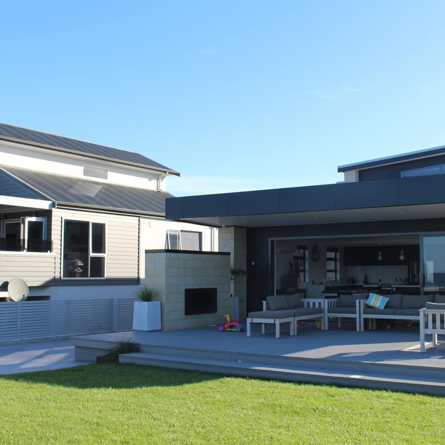 Modern beachside cottage with outdoor fireplace, deck with cushioned outdoor furniture and sliding glass doors