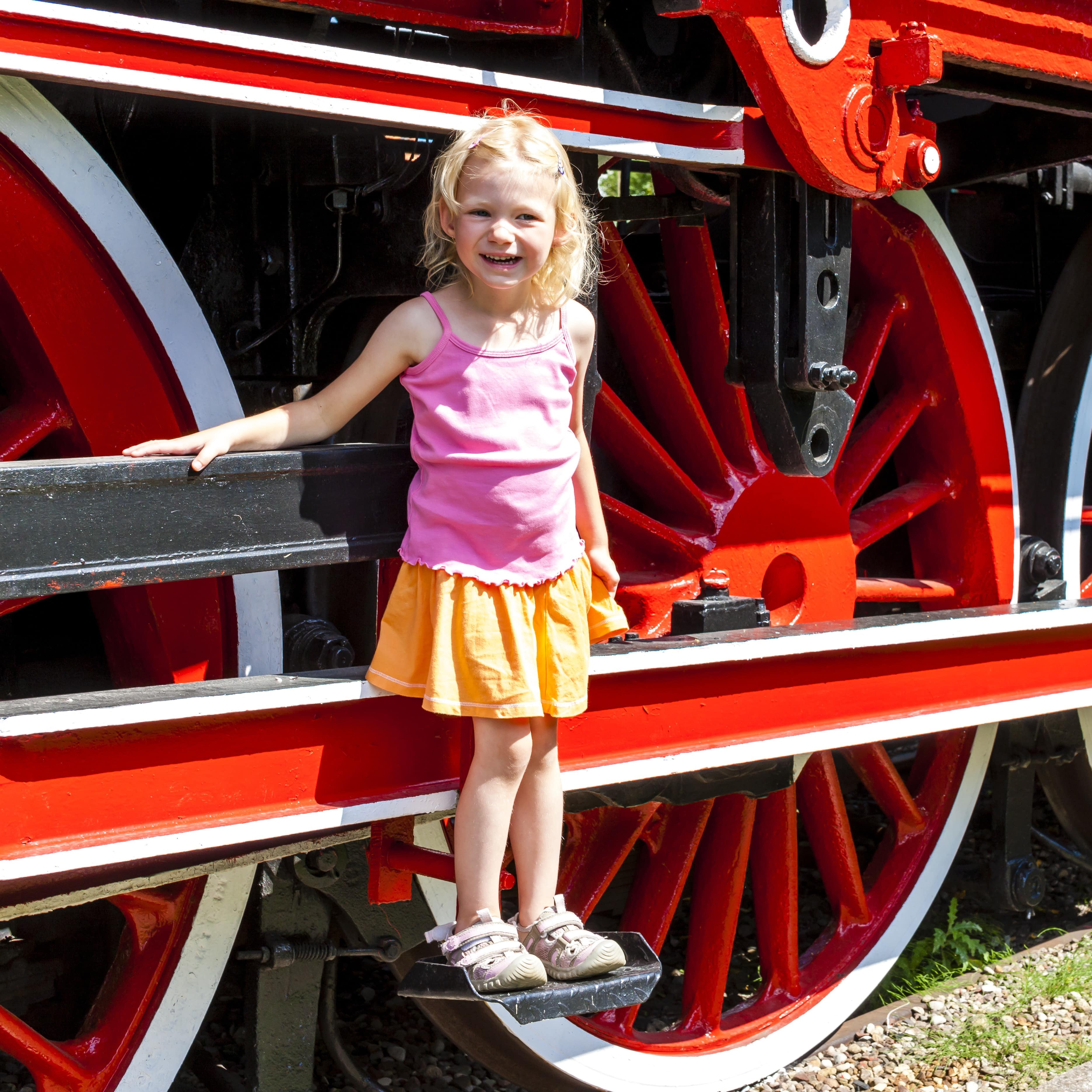 Little girl standing on step of antique locomotive