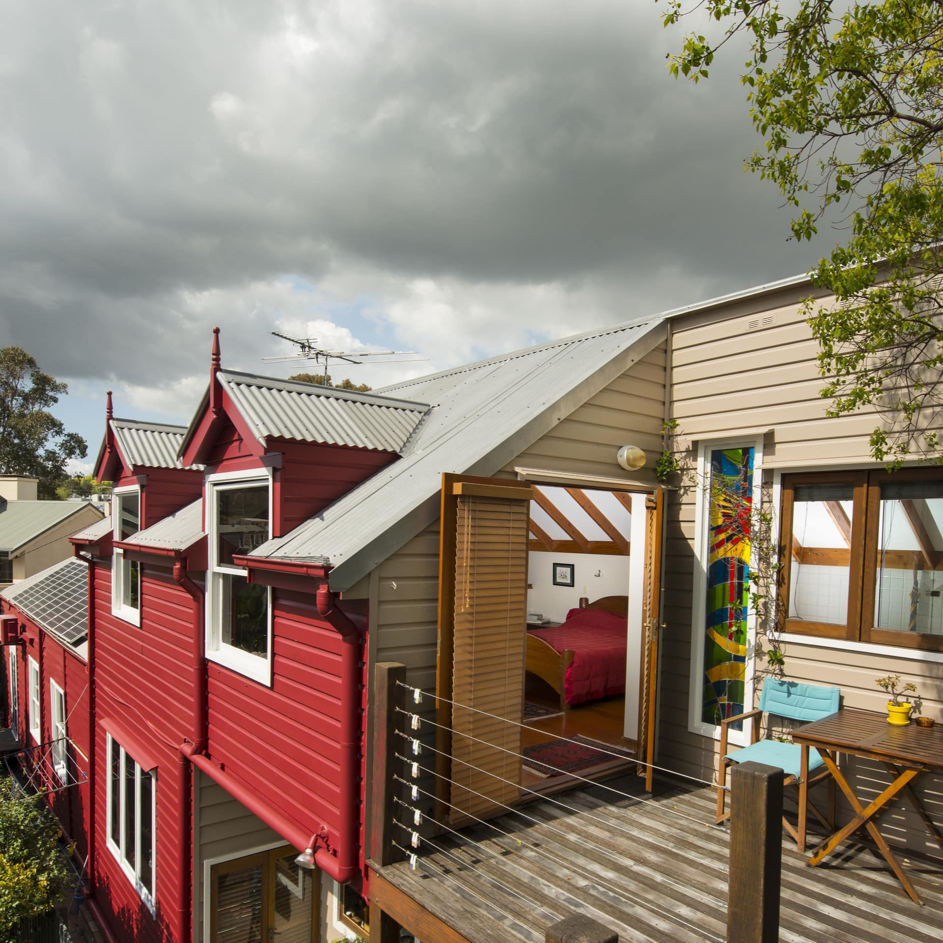 Eco-friendly red and beige bed and breakfast with private patios with chairs and tables for outdoor eating and catching views