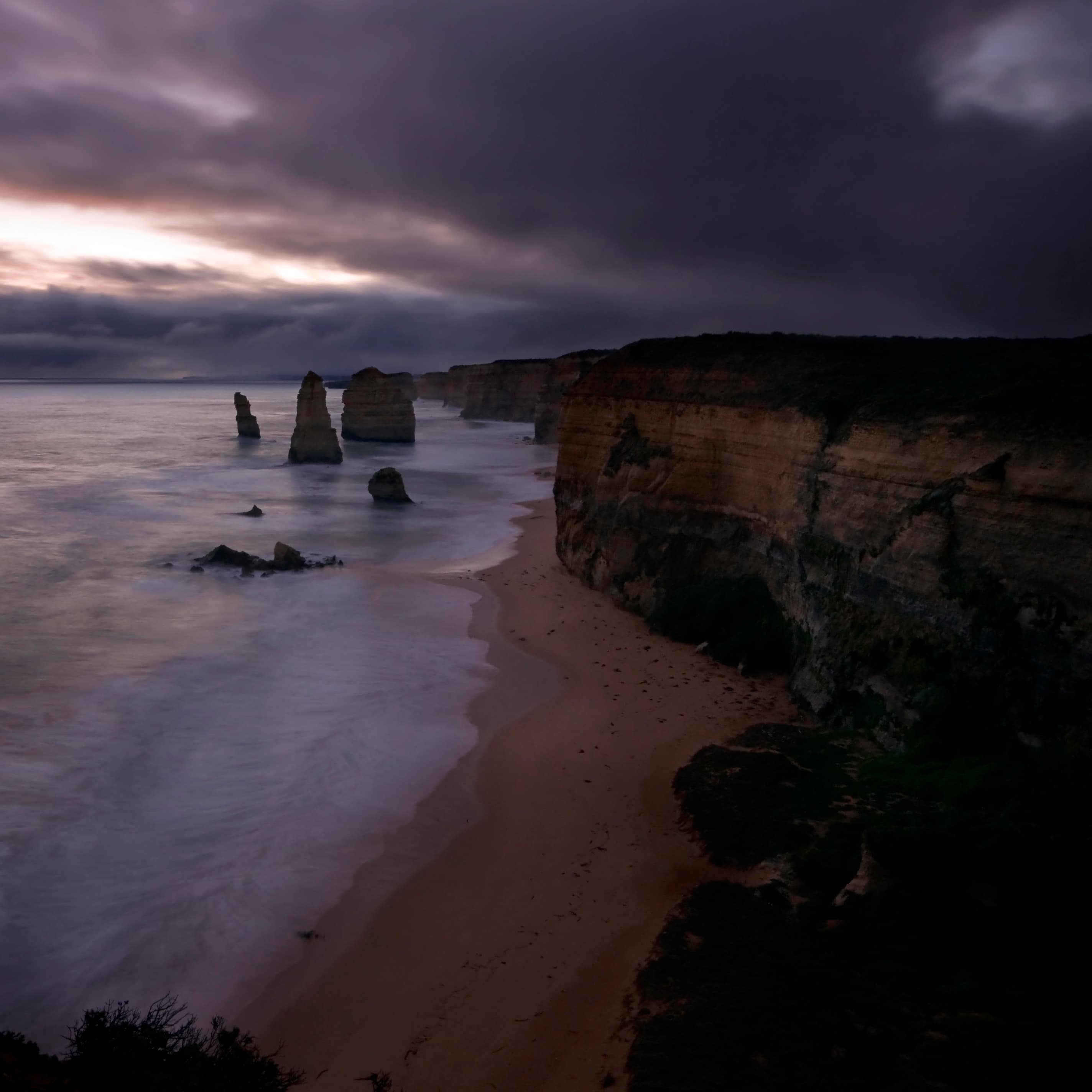 Stacks in the water off of the Victoria coastline at sunset with a purple sky, sea and cliffs