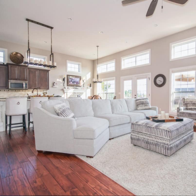 Family-friendly apartment with soft, white cloth sectional and rug, breakfast bar and kitchen with windows along the wall