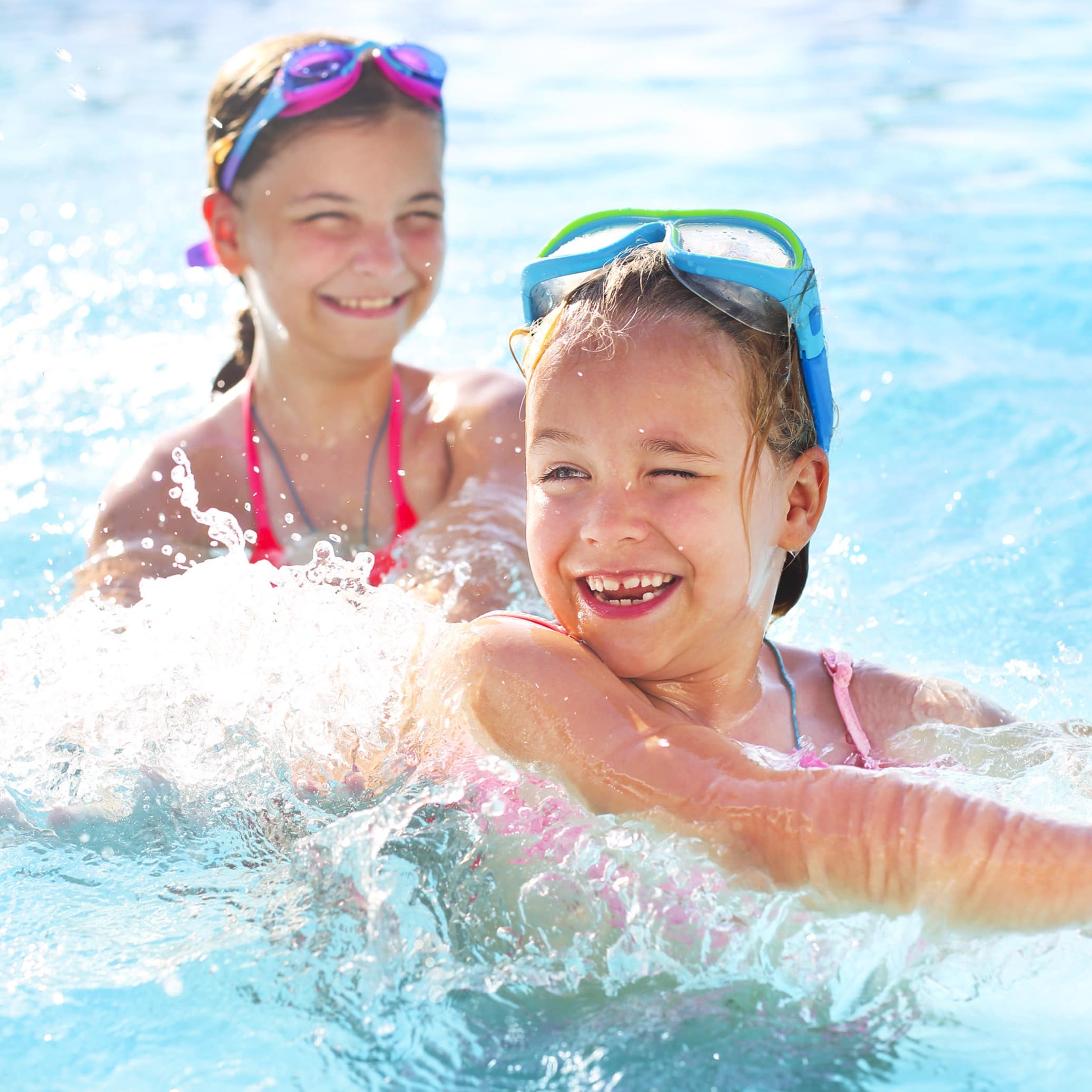 Two cute girls playing in water pool at park