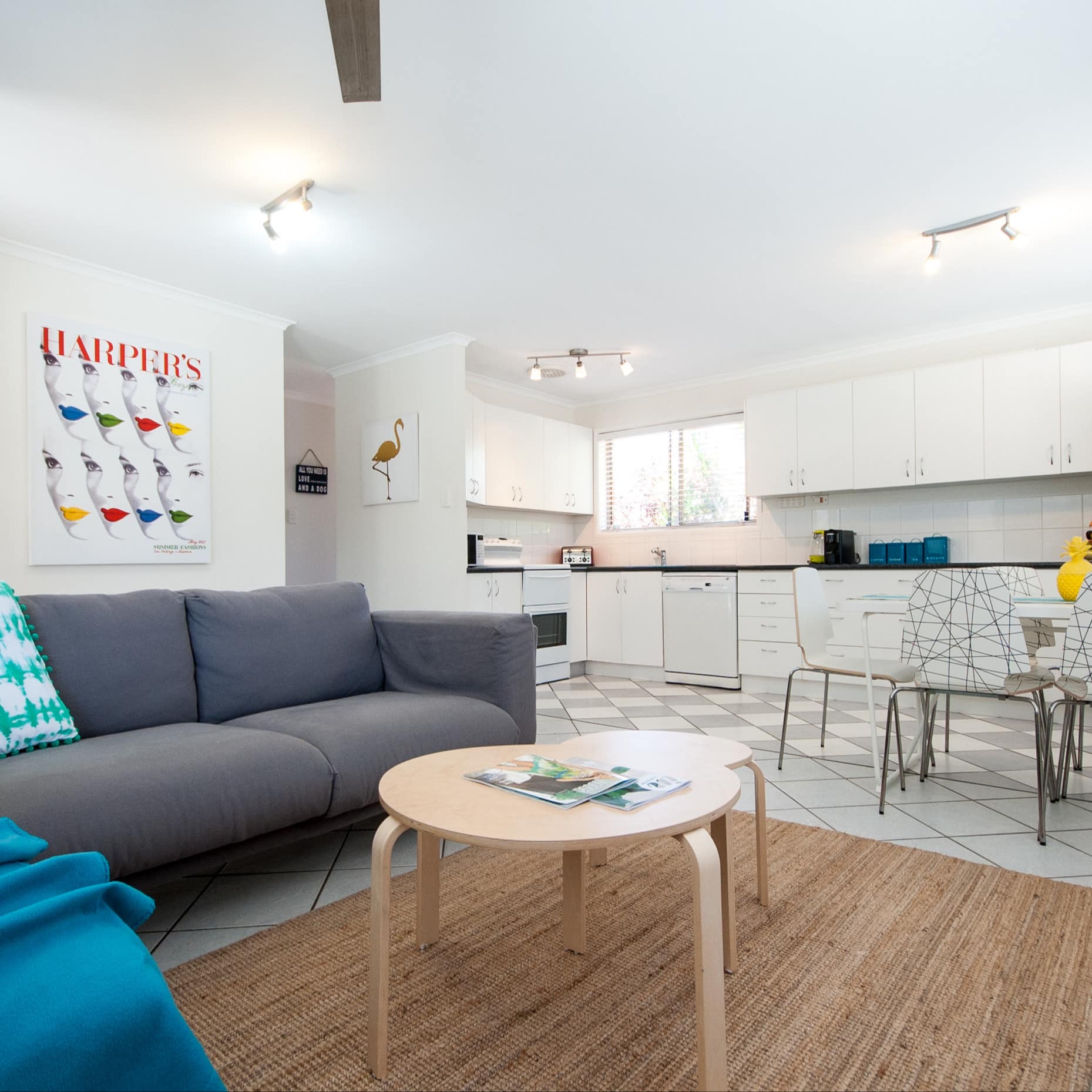 Living area of 3-bedroom villa with tile floor, grey sofa, wooden tables and dining set