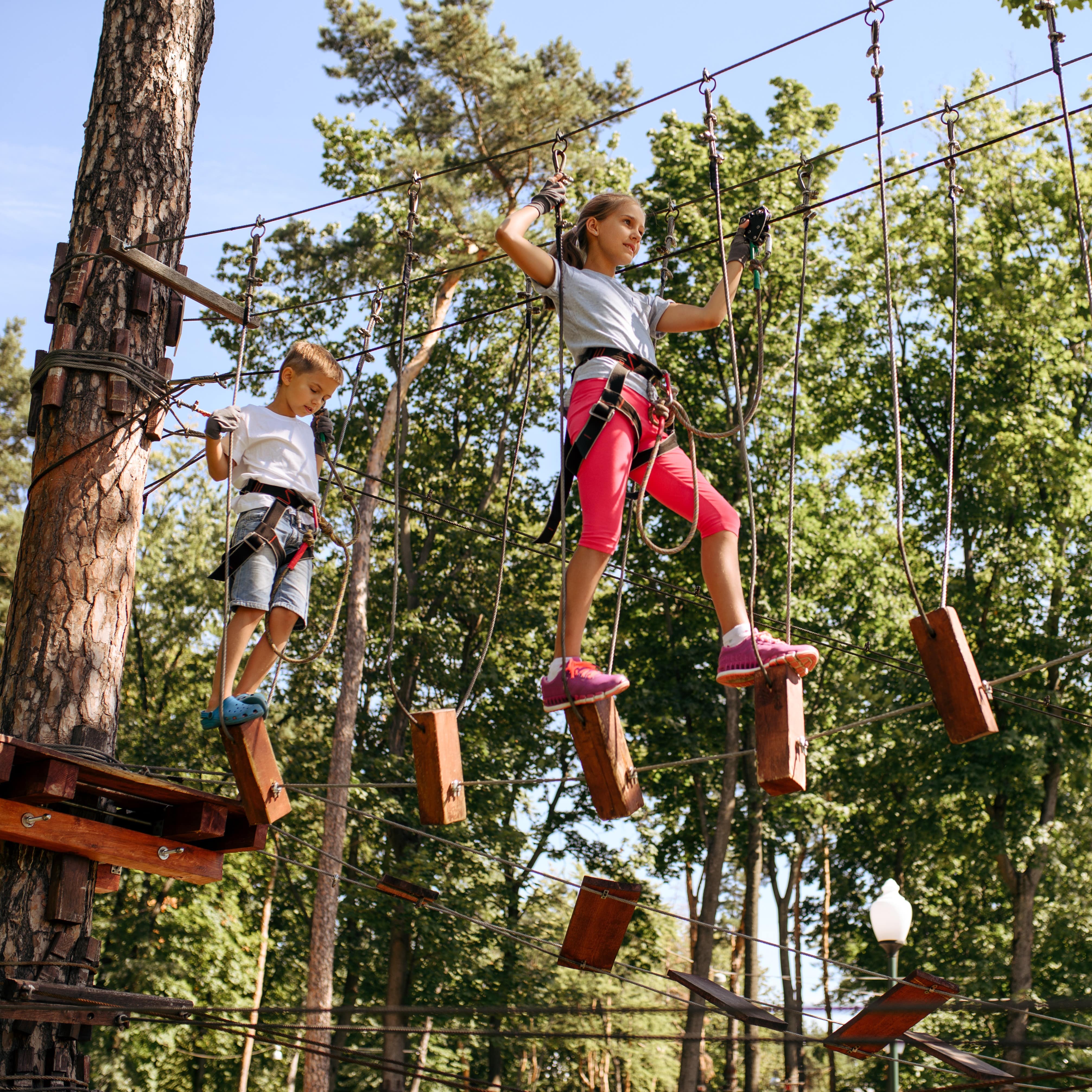 Two kids maneuvering ropes course