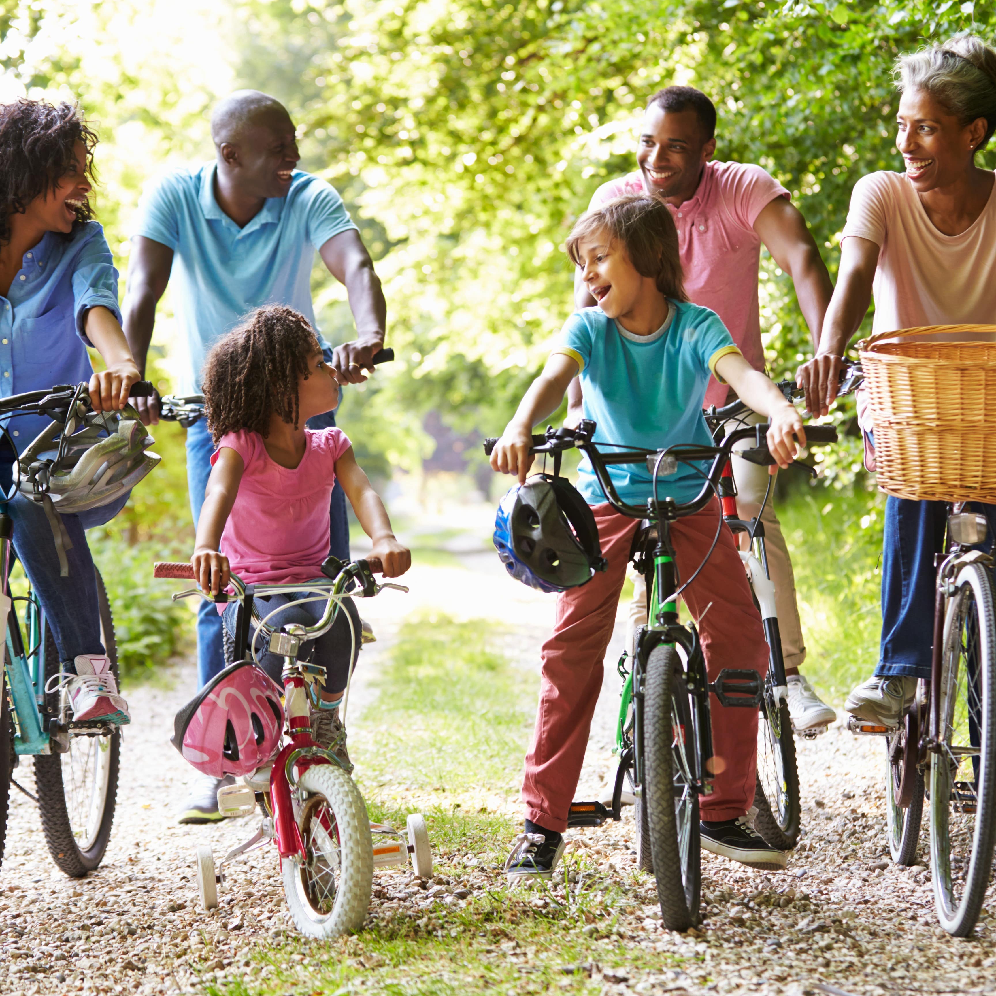 Multi generation family of six riding bikes on a path