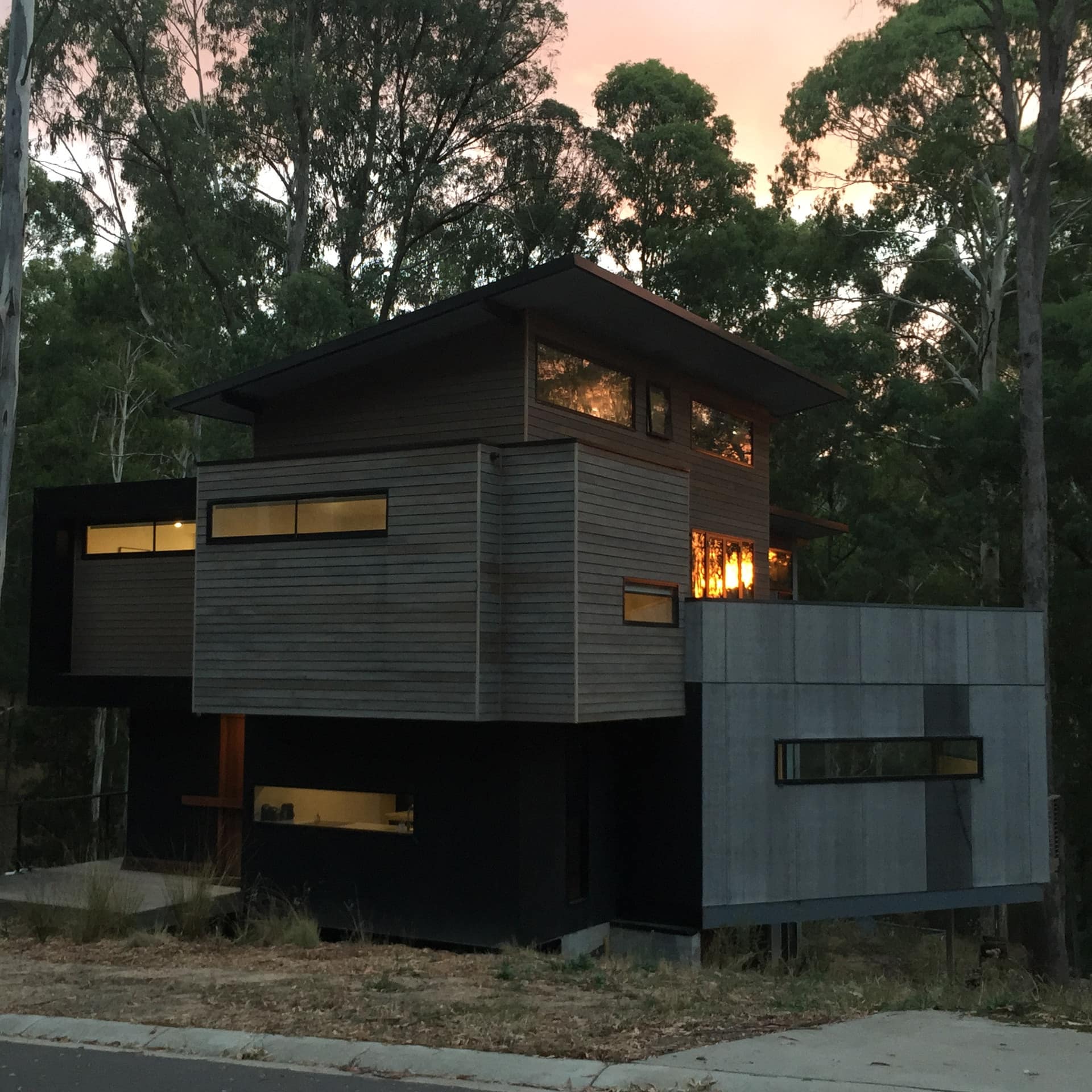 Exterior view of unusually-shaped 3-storey modern wood chalet at sunset