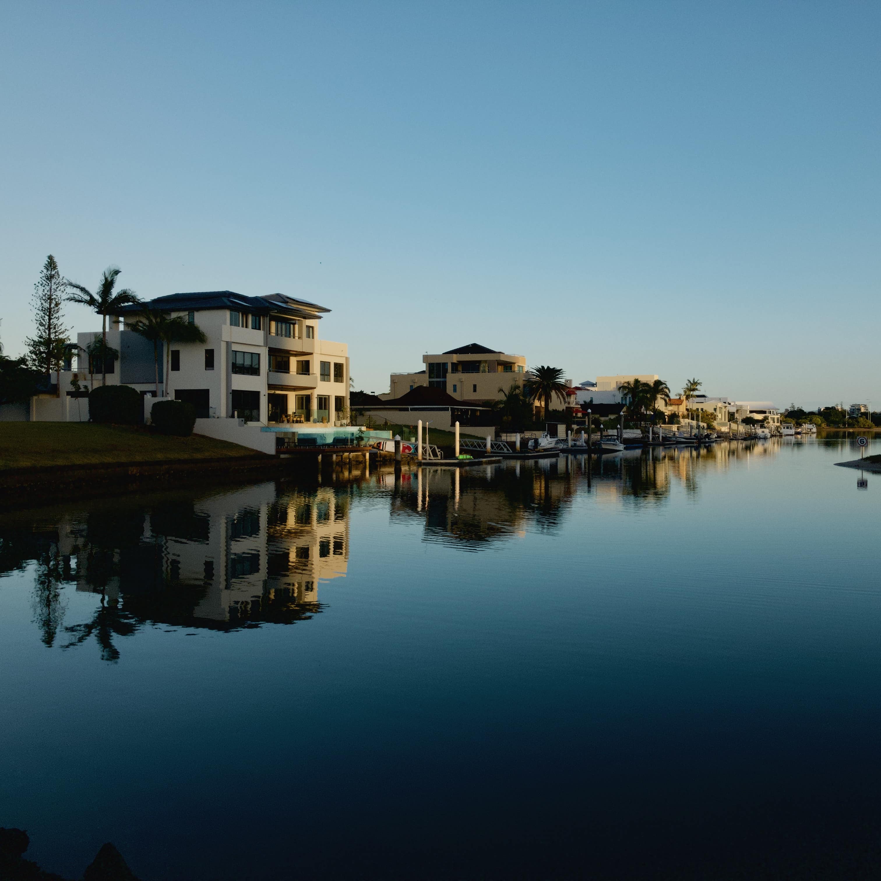 3-storey villas on the waterfront of the Gold Coast at dusk with reflections on the water and boats docked at piers