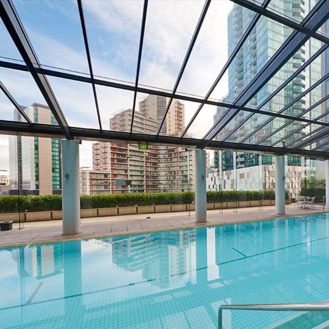 A large pool with glass roof surrounded by skyscrapers.