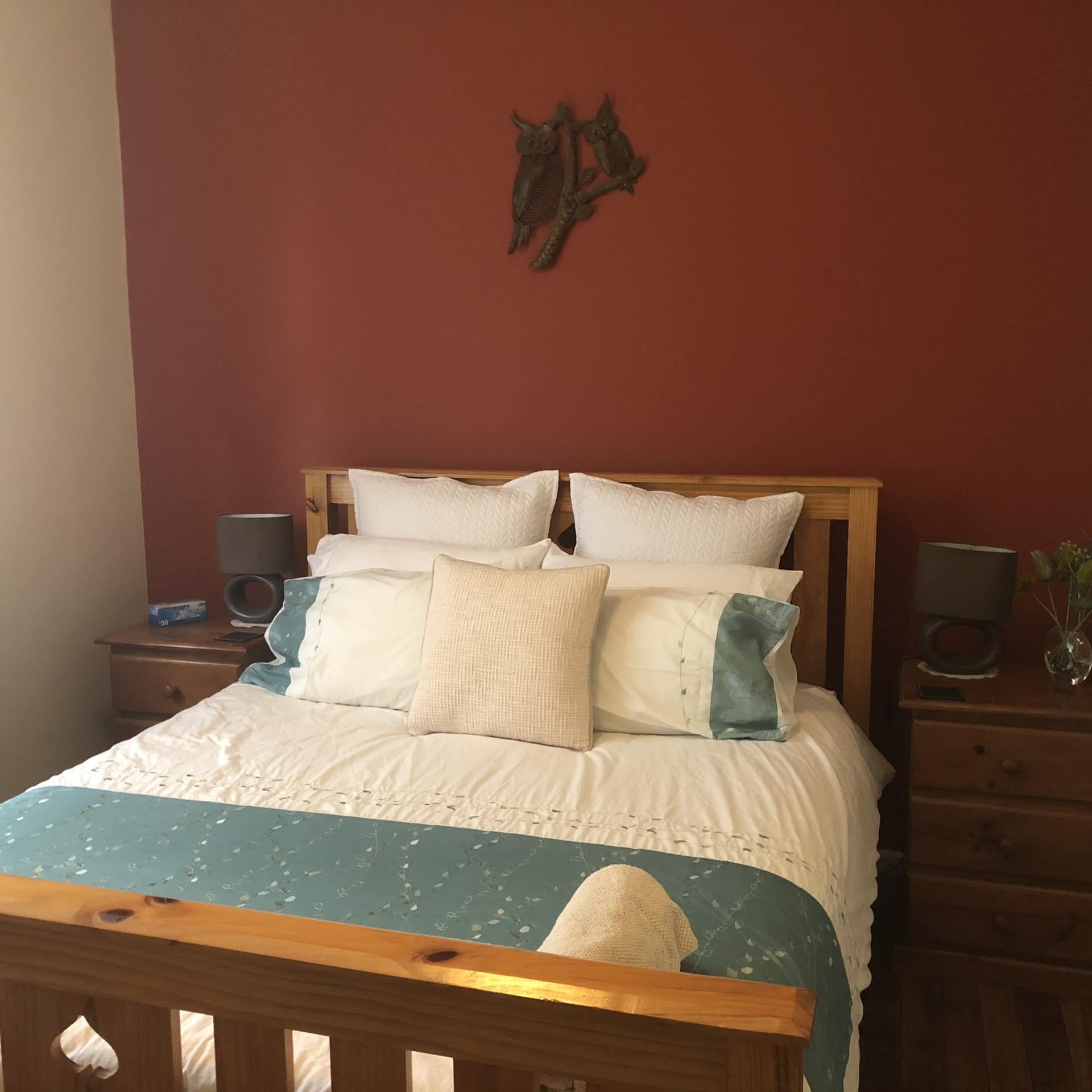 Bedroom with red accent wall, wood-framed queen-size bed, blue and white bedding, matching wood bedside tables.