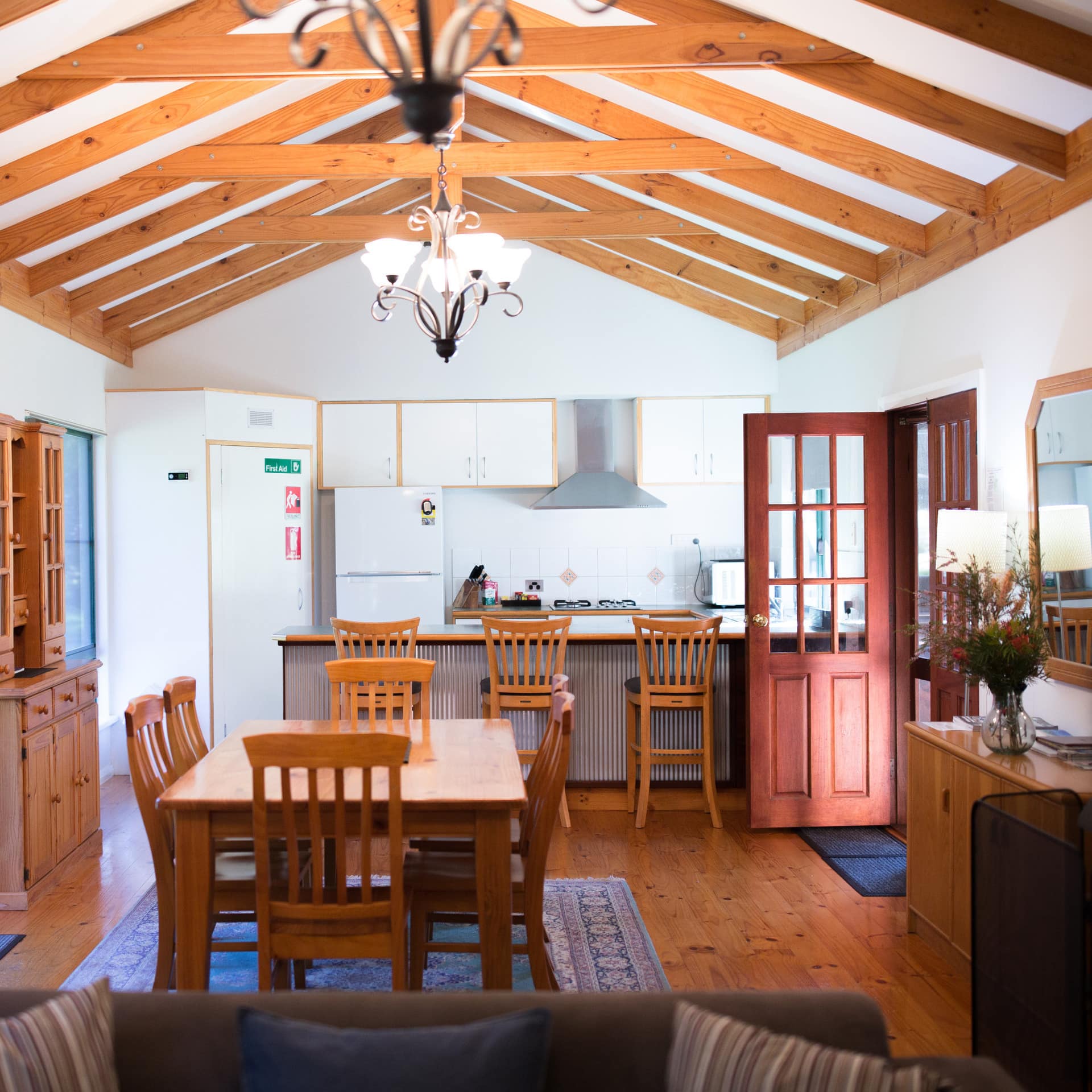 Open kitchen with hardwood floors, and vaulted ceilings, wooden dining set, white cabinets and countertops.