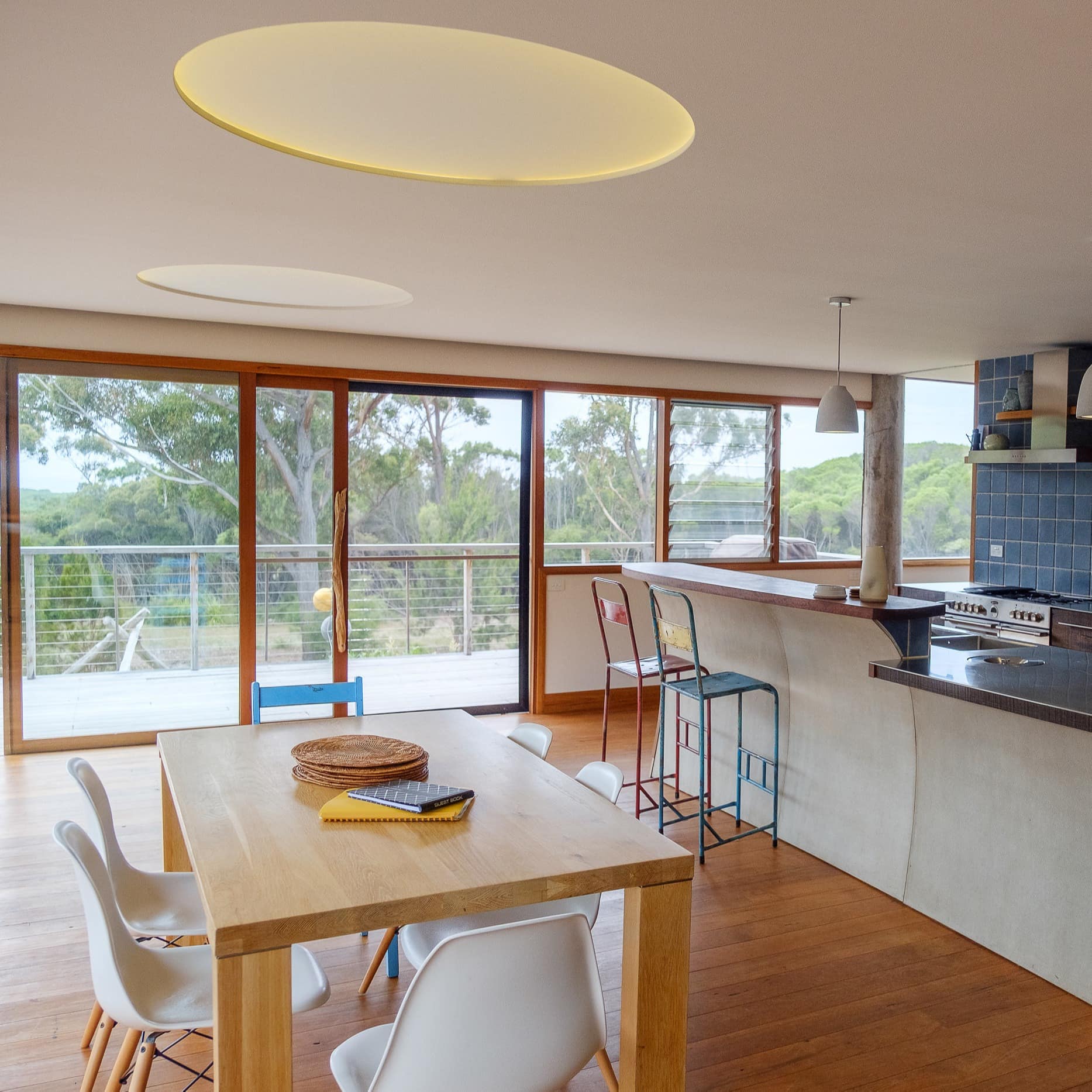 Spacious kitchen and eating area decorated with wood, steel, and tile with view of patio outside of large windows