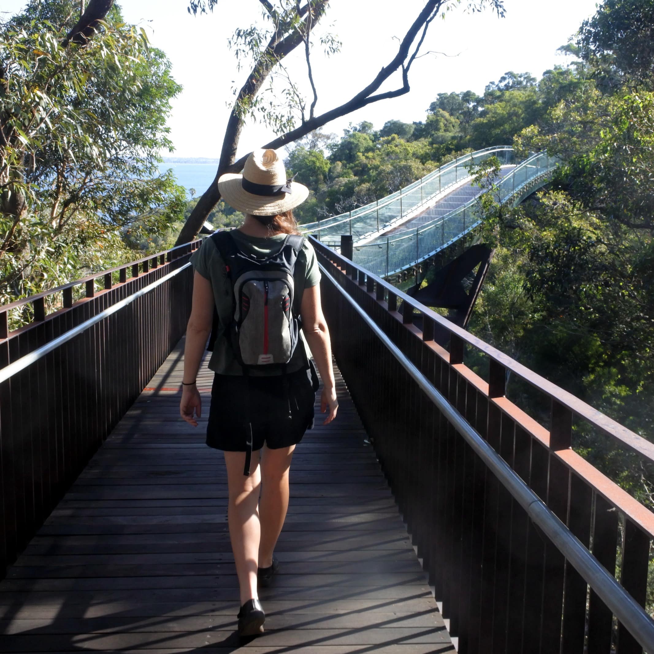 Lady walking on Perth walkway toward a glass arched bridge in Western Australia