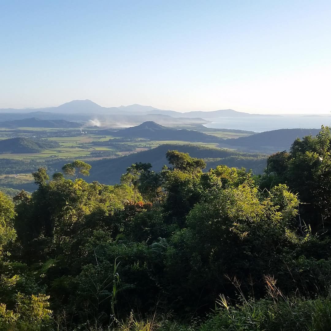 Long-distance view of Port Douglas from a forested mountaintop with the valleys and mountains of Port Douglas and the bay