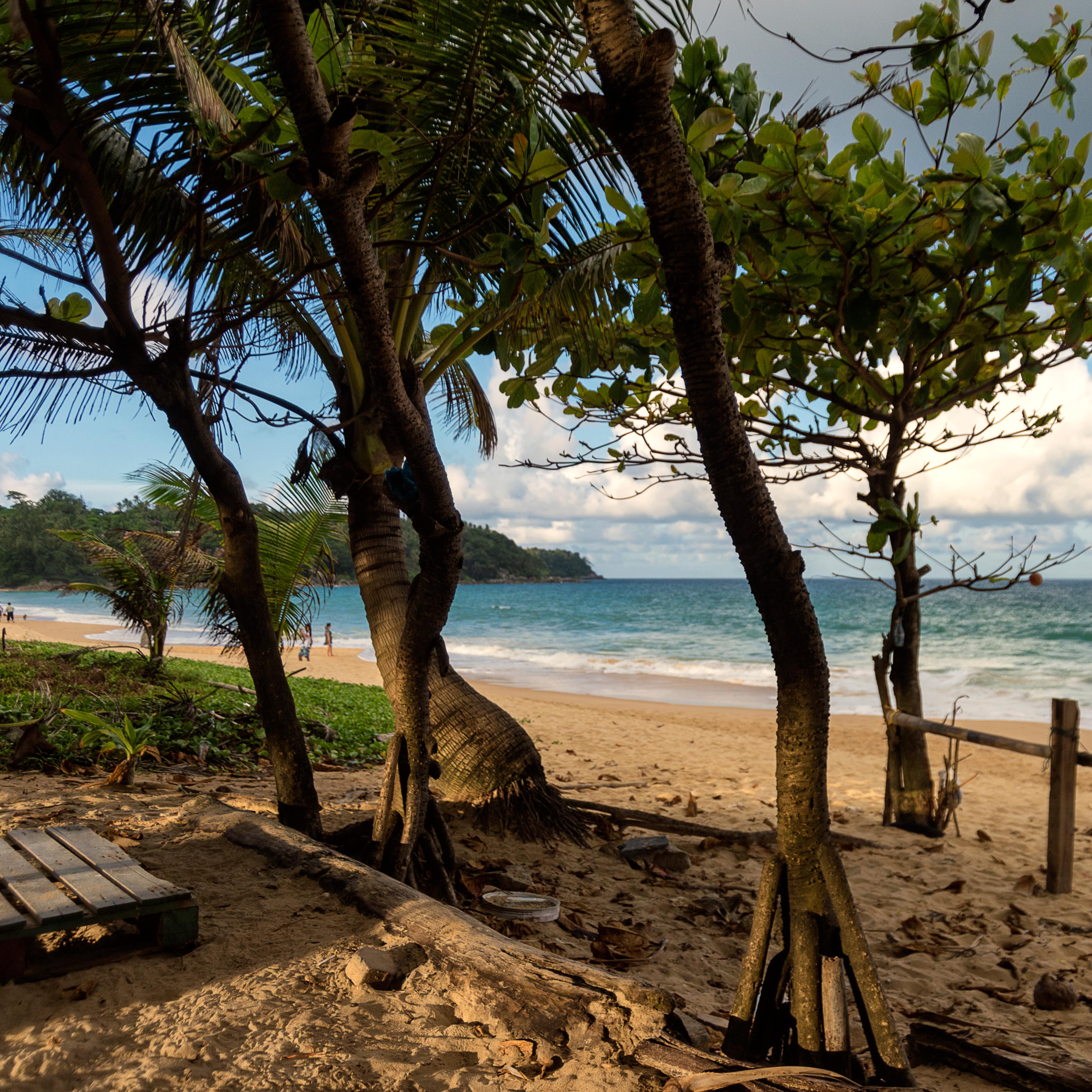 View of Karon Beach, Phuket, with white puffy clouds, golden sands, green seas and tropical vegetation