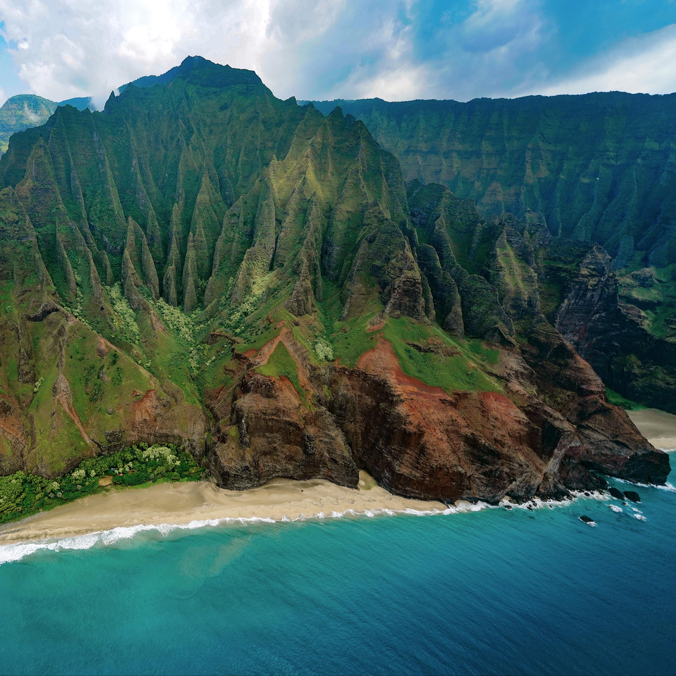Aerial view of Kālepa Ridge, Hawaii, with steep faults covered in plants and rock formed from lava spilling to the Pacific