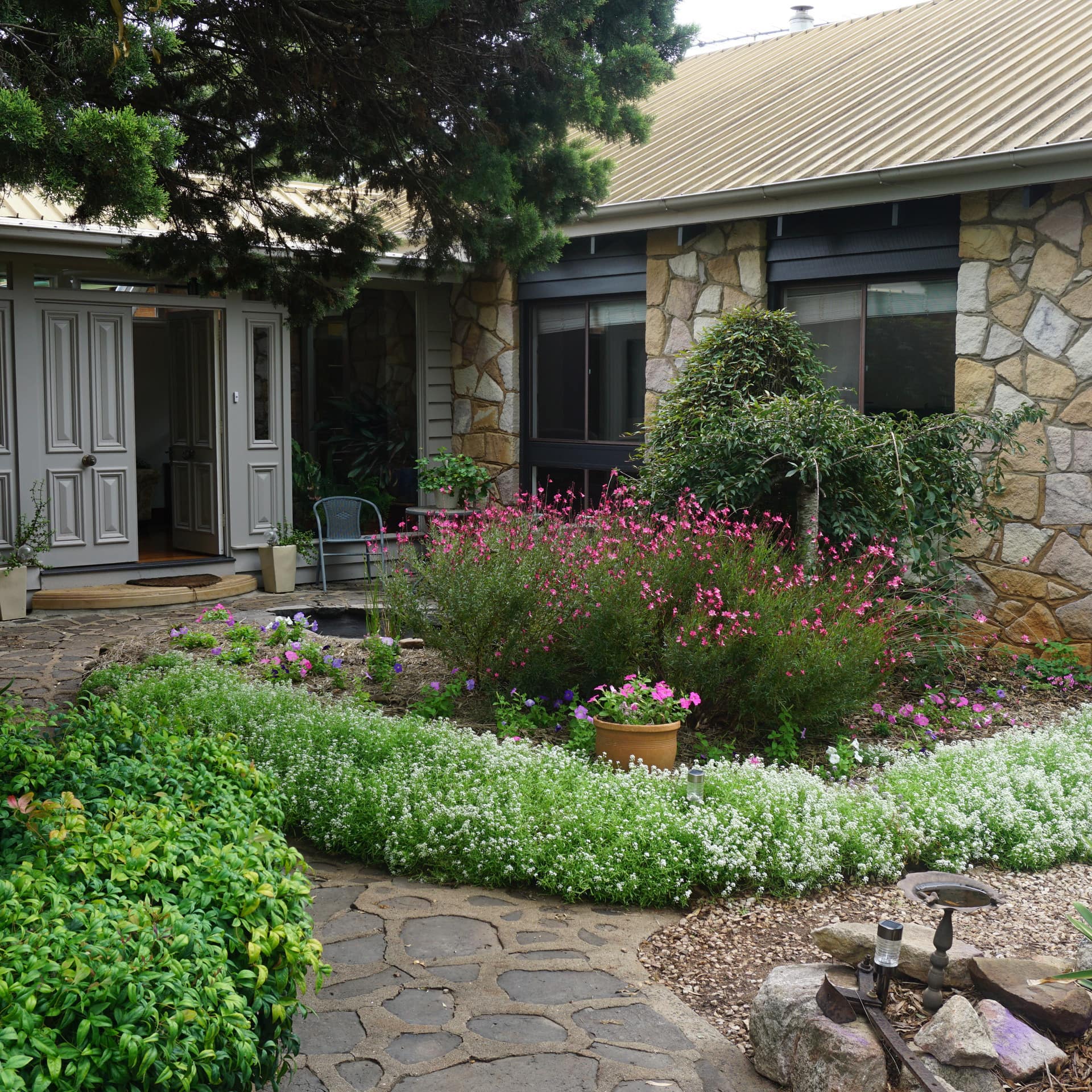 Rural 2-bedroom cottage with natural stone walls, grey double front doors and a landscaped garden.