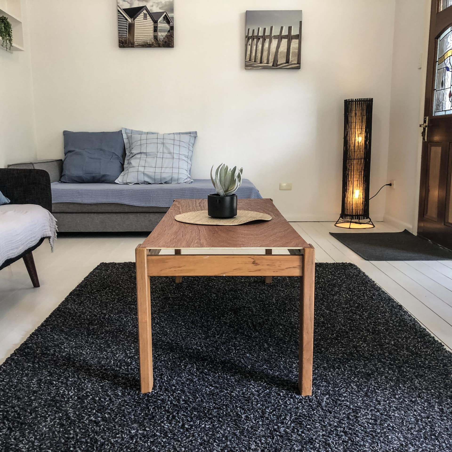 Modern living room with wood floors, grey and black sofas, wooden coffee table, black shag rug.